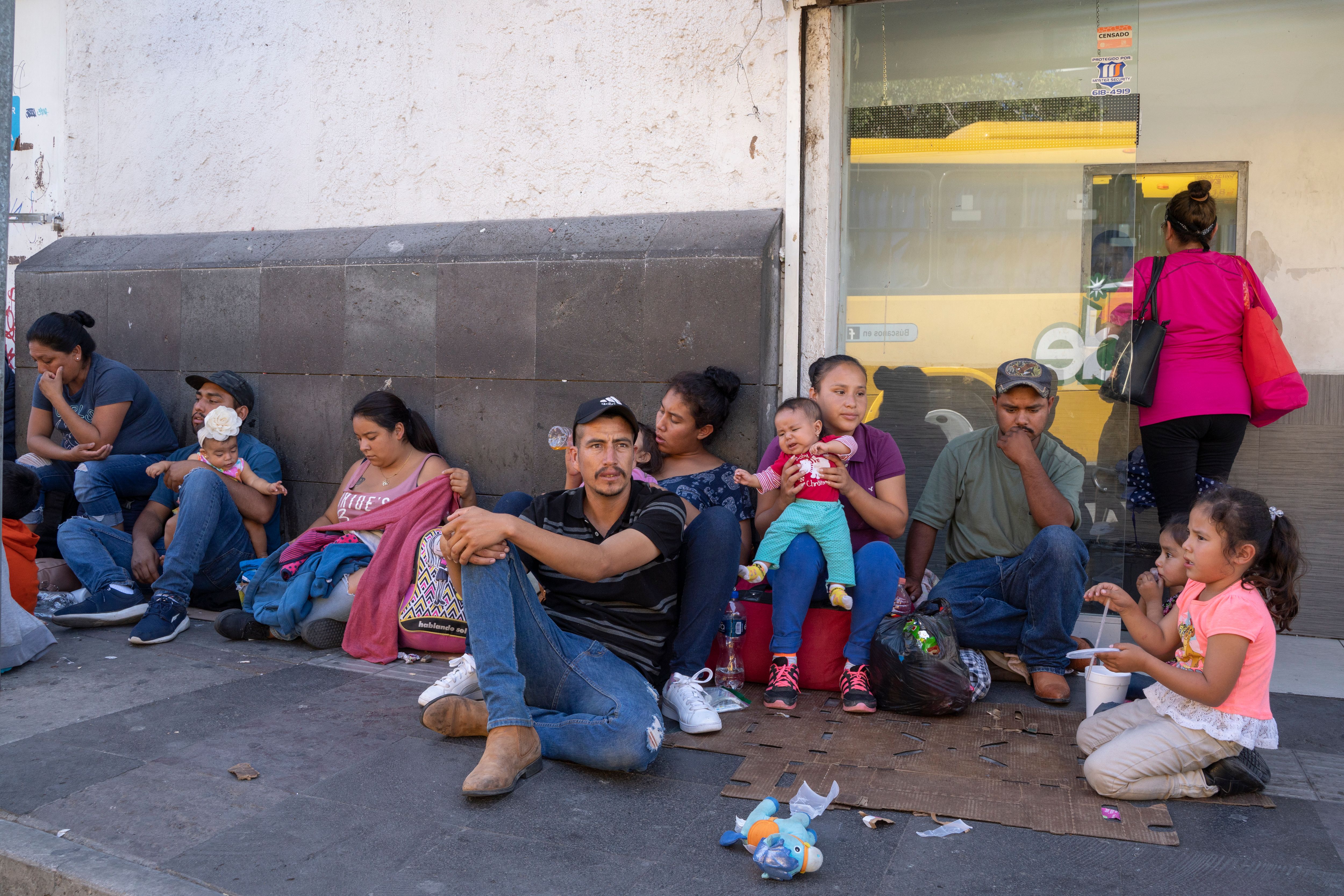 Migrants, mostly from Mexico, are pictured sitting on the ground waiting near the Paso del Norte Bridge at the Mexico-US border, in Ciudad Juarez, Mexico, on September 12, 2019. (Credit: PAUL RATJE/AFP/Getty Images)