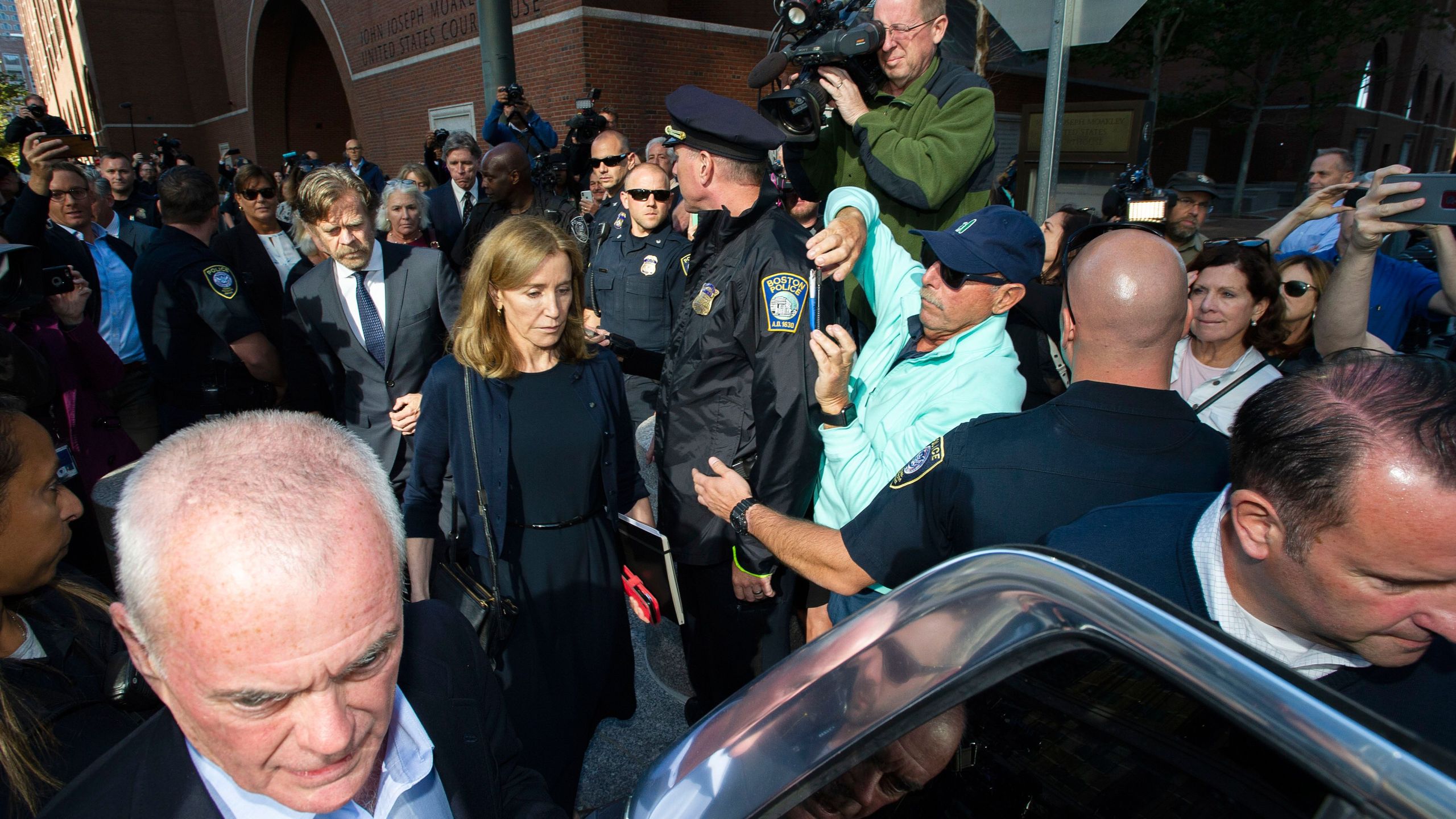 Felicity Huffman, escorted by her husband William H. Macy, leaves the John Joseph Moakley U.S. Courthouse in Boston, where she was sentenced for her role in the college admissions scandal, on Sept. 13, 2019. (Credit: JOSEPH PREZIOSO/AFP/Getty Images)