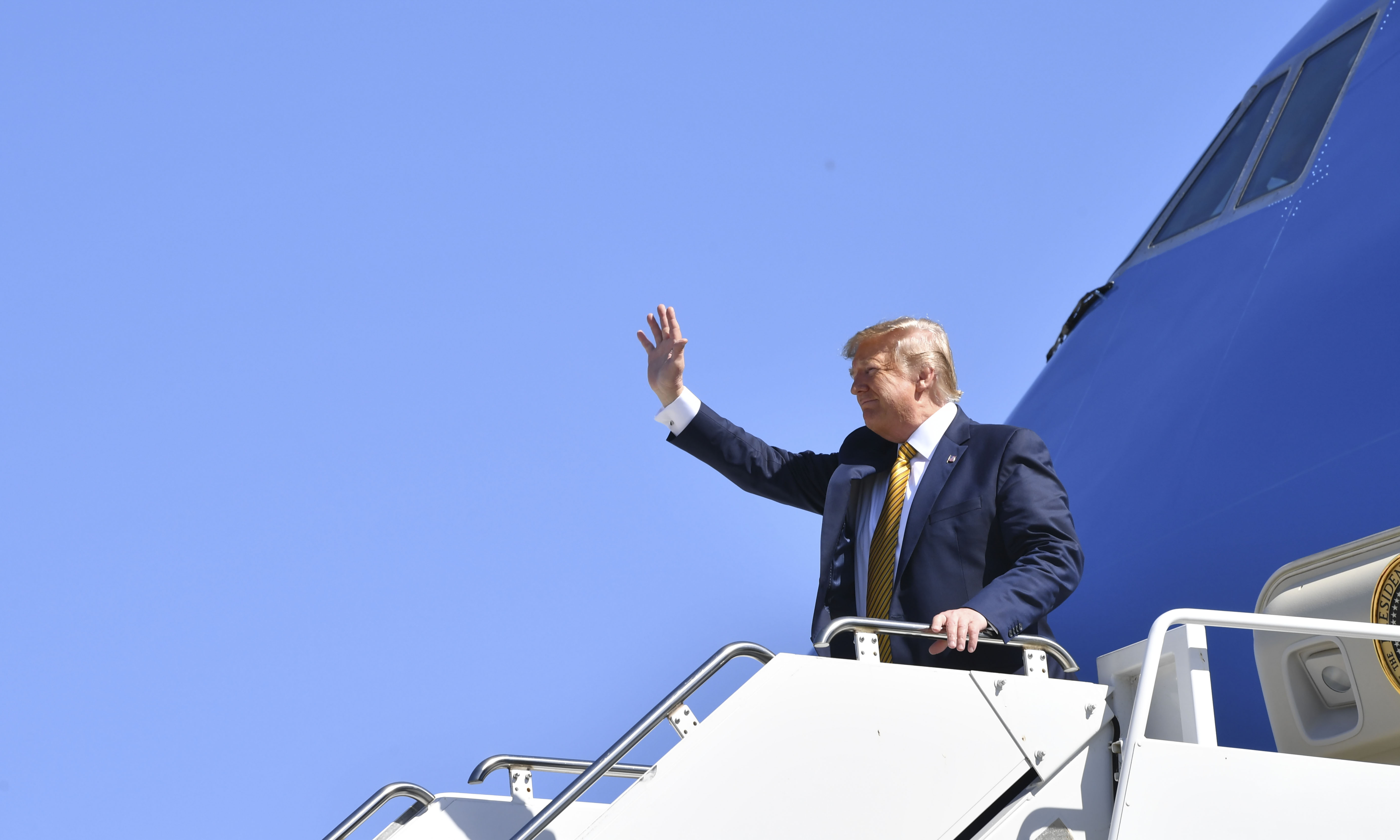 President Donald Trump waves from Air Force One after landing in Santa Clara County for fundraising events in California. (Credit: Nicholas Kamm / AFP / Getty Images)