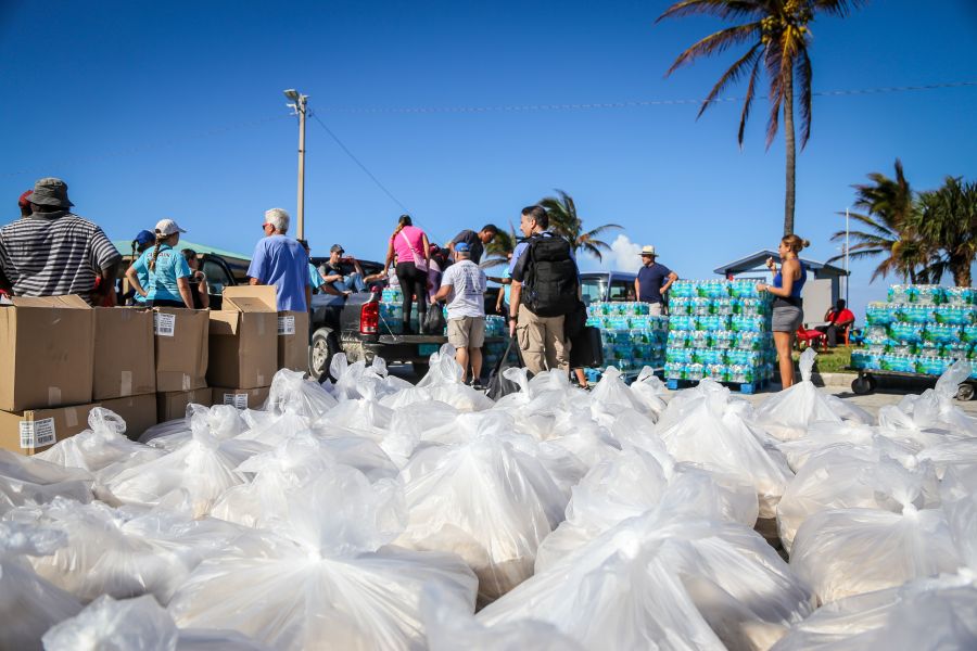 People from the Bahamas Relief Cruise, operated by the Bahamas Paradise Cruise Line, stand next to some 20,000 meals prepared for Bahamians to be delivered to distribution centers and homes in the aftermath of Hurricane Dorian and Tropical Storm Humberto in Freeport, Grand Bahama, Bahamas, on Sept. 17, 2019. (Credit: ZAK BENNETT/AFP/Getty Images)