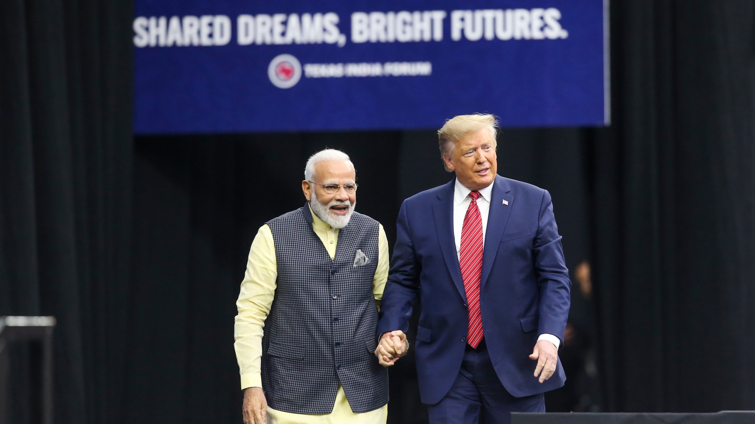 India Prime Minister Narendra Modi and President Donald Trump hold hands at the Community Summit on Sept. 22, 2019, at NRG Stadium in Houston, Texas. (Credit: Thomas B. Shea/AFP/Getty Images)