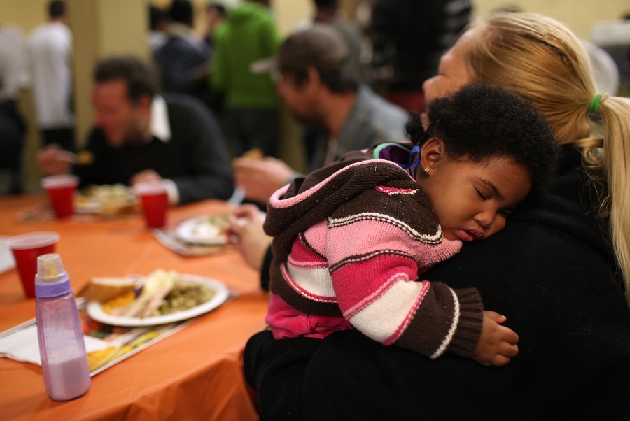 Eight month-old Canziz Lynch sleeps as people enjoy a free Thanksgiving meal at CityTeam Ministries on Nov. 23, 2011, in San Francisco. CityTeam Ministries in San Francisco fed nearly 400 Thanksgiving meals to homeless and underprivileged people that year. (Credit:Justin Sullivan/Getty Images)