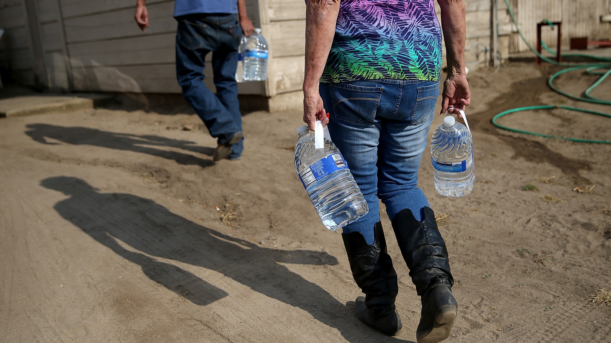 Donna Johnson (R) delivers drinking water to a resident who has no running water on April 23, 2015, in Porterville, Calif. (Credit: Justin Sullivan/Getty Images)