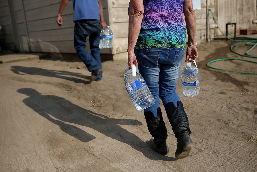 Donna Johnson (R) delivers drinking water to a resident who has no running water on April 23, 2015, in Porterville, Calif. (Credit: Justin Sullivan/Getty Images)