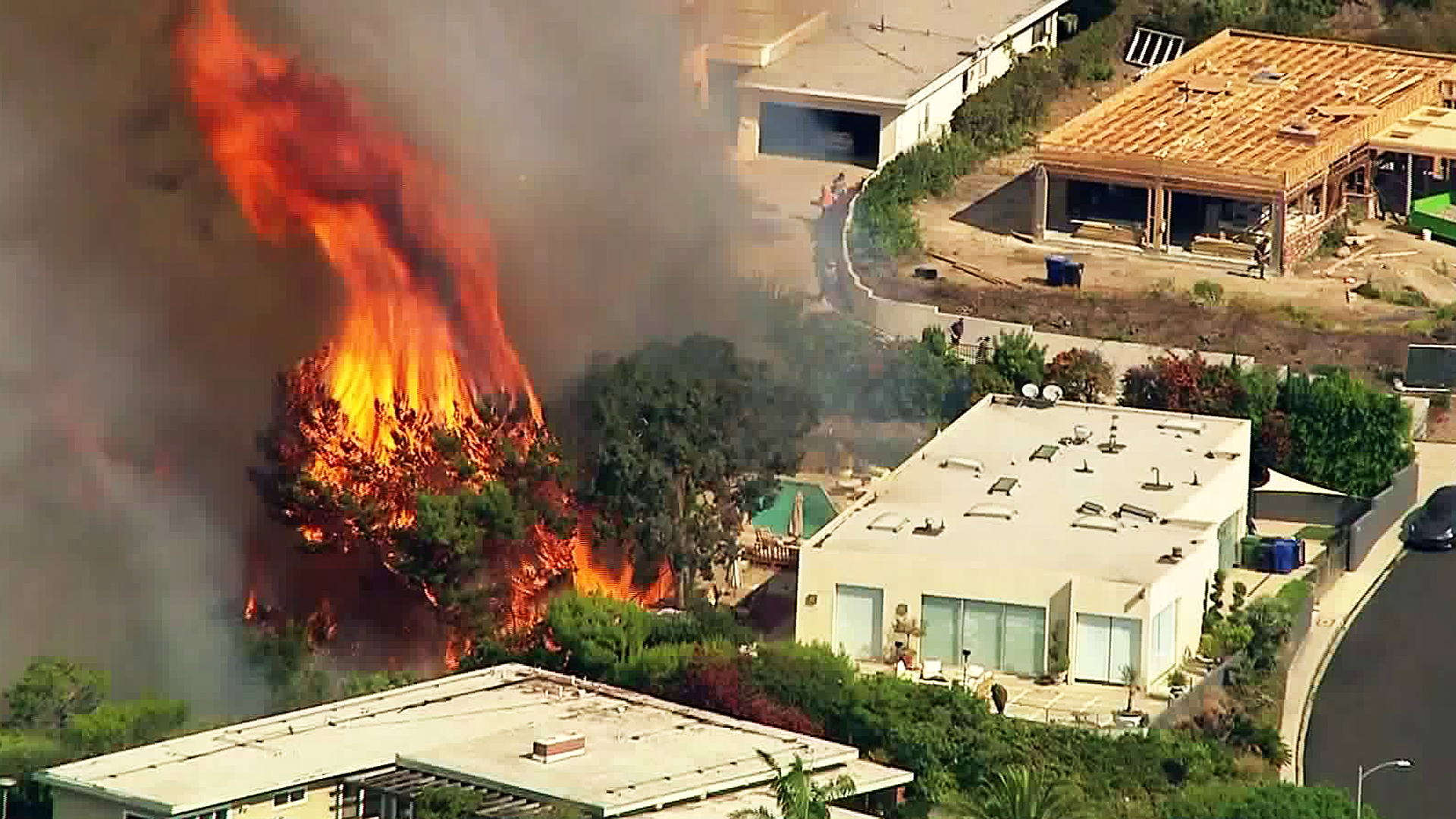 A brush fire burns near a home in Pacific Palisades on Oct. 21, 2019. (Credit: KTLA)