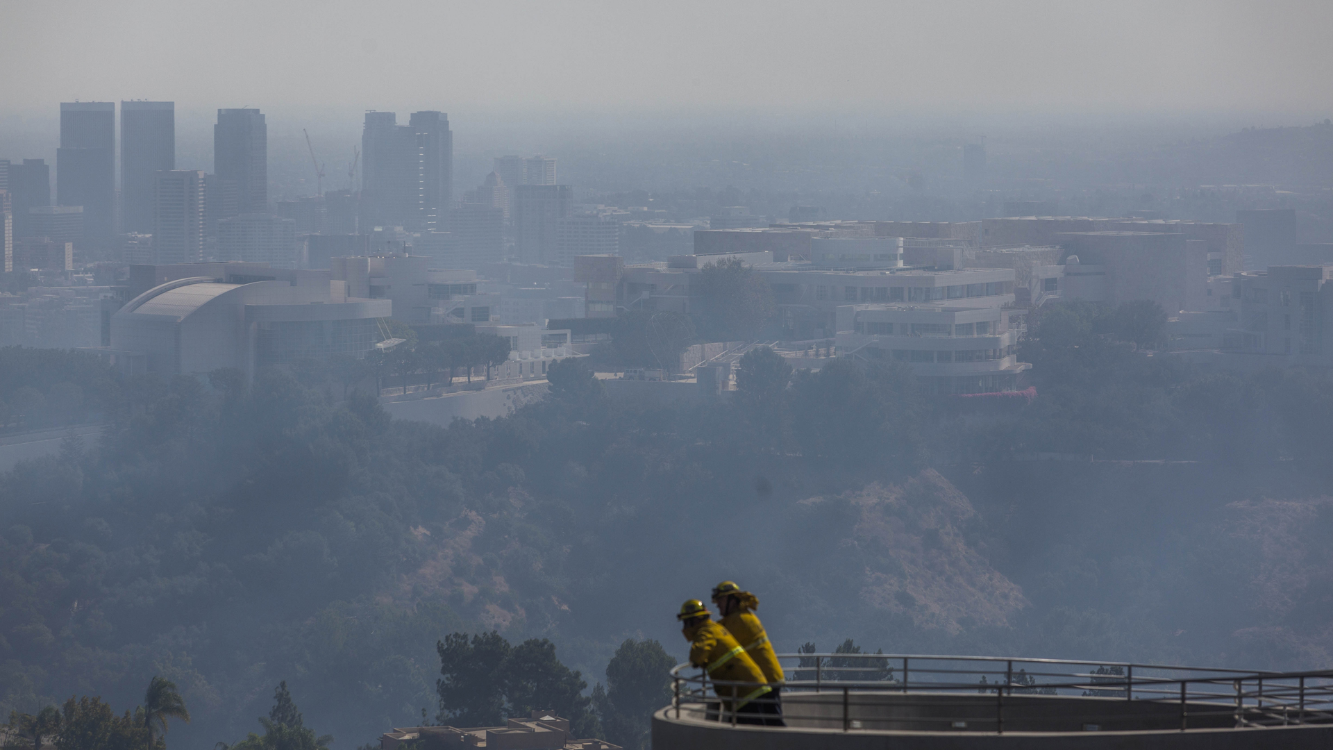 Firefighters stand on a balcony overlooking the Getty Center as the Getty Fire burns in Brentwood on Oct. 28, 2019. (Credit: Apu Gomes / AFP / Getty Images)