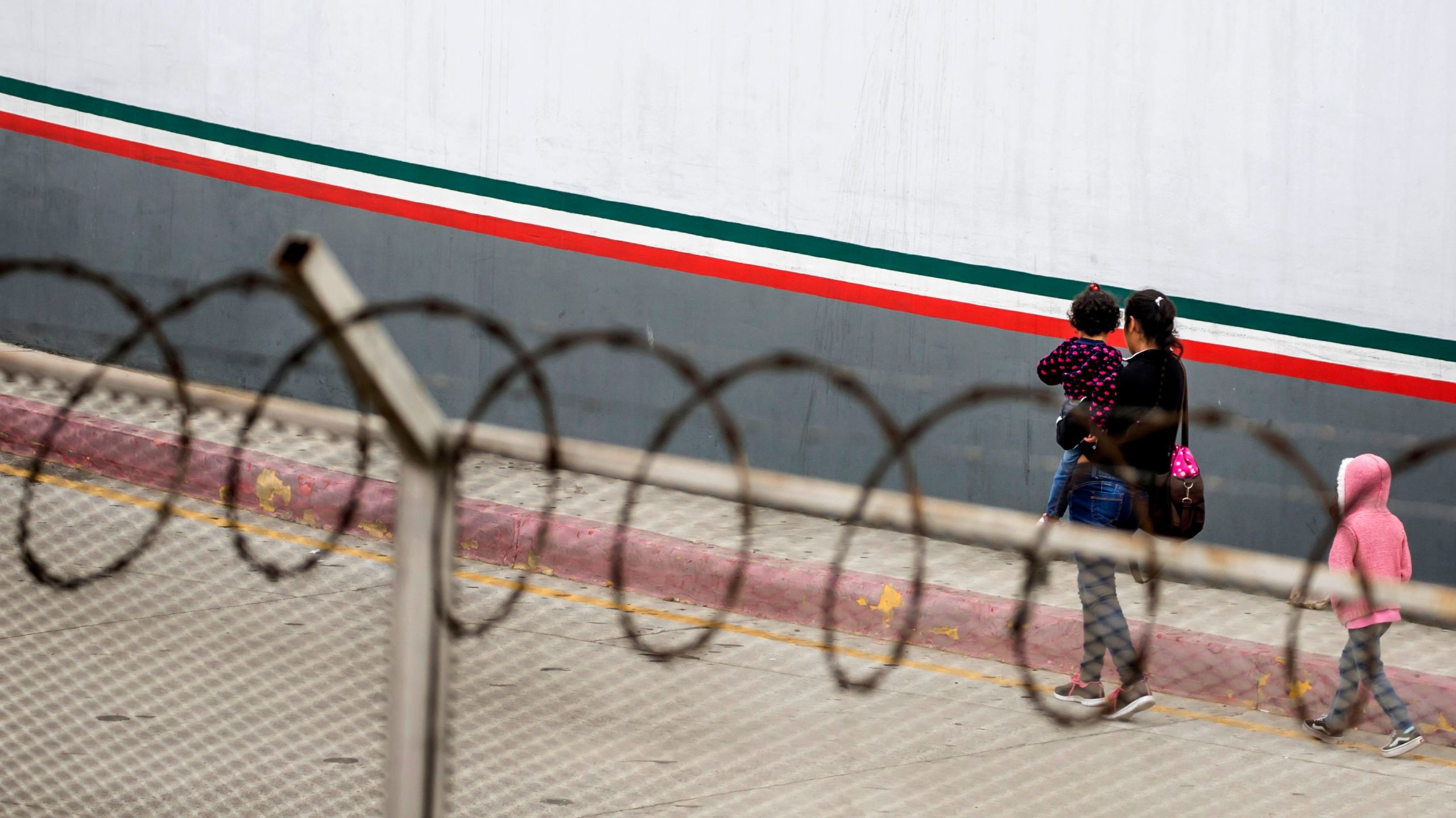 A Central American migrant and her children walk outside El Chaparral port of entry, in Tijuana, Mexico, on July 17, 2019. (Credit: Omar Martínez / AFP / Getty Images)