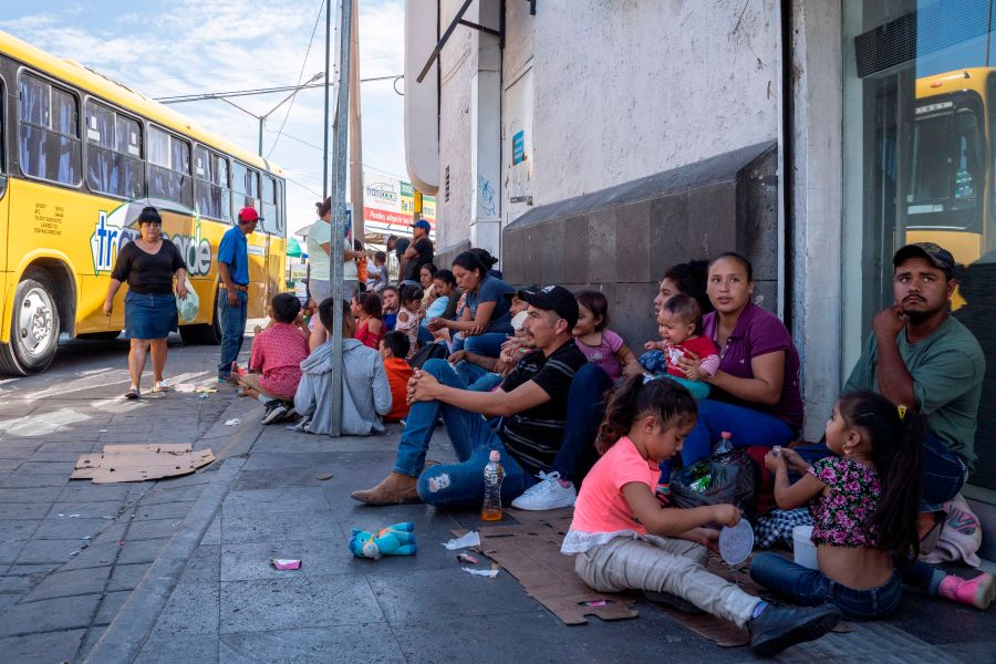 Migrants, mostly from Mexico, sit on the ground as they wait near the Paso del Norte Bridge at the Mexico-U.S. border in Ciudad Juarez, Mexico, on Sept. 12, 2019. (Credit: Paul Ratje / AFP / Getty Images)