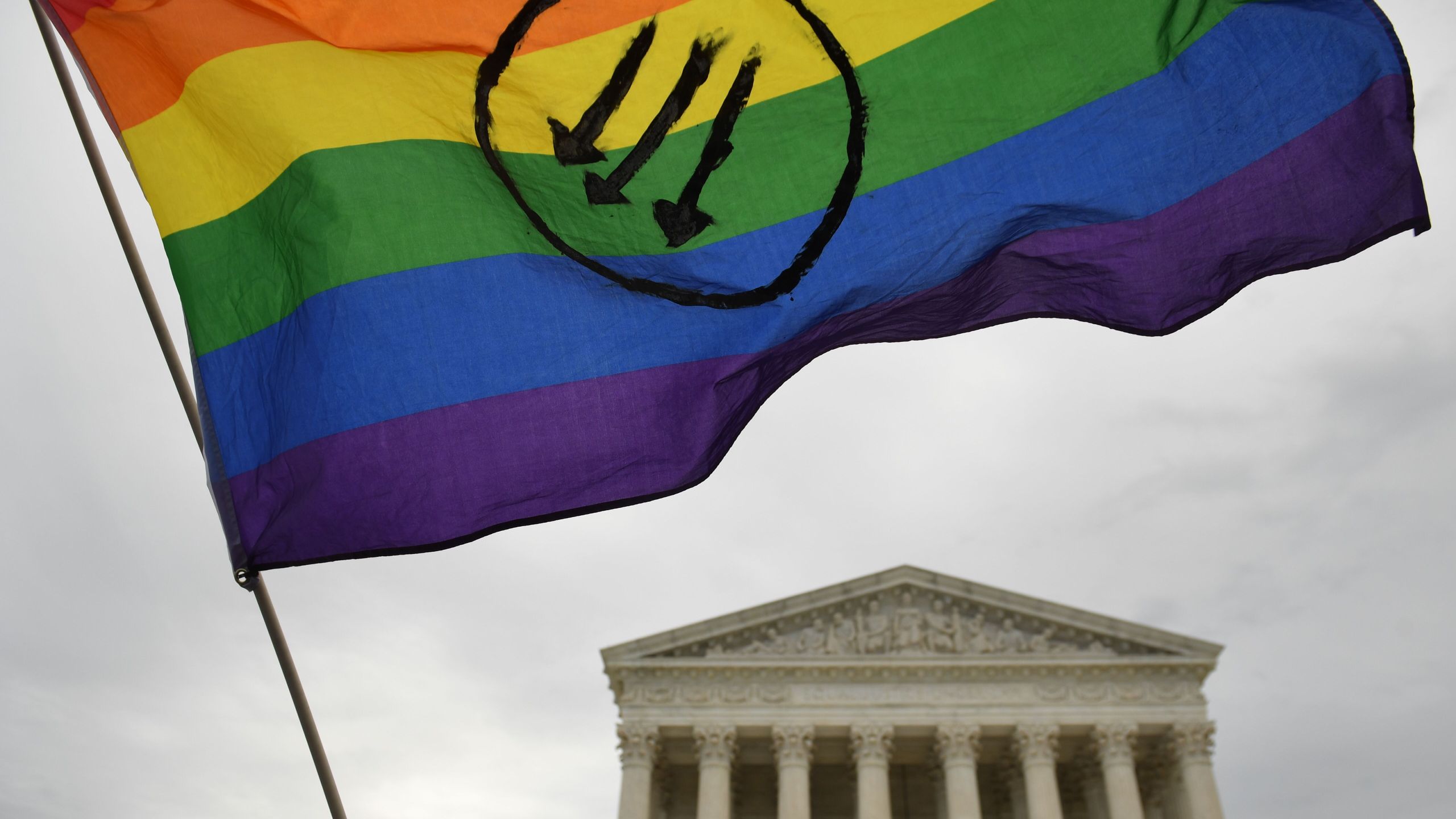 Demonstrators hold up a rainbow flag at an LGBT rights rally outside the U.S. Supreme Court in Washington, D.C., on Oct. 8, 2019, as the court holds oral arguments in cases dealing with workplace discrimination based on sexual orientation. (Credit: SAUL LOEB/AFP via Getty Images)