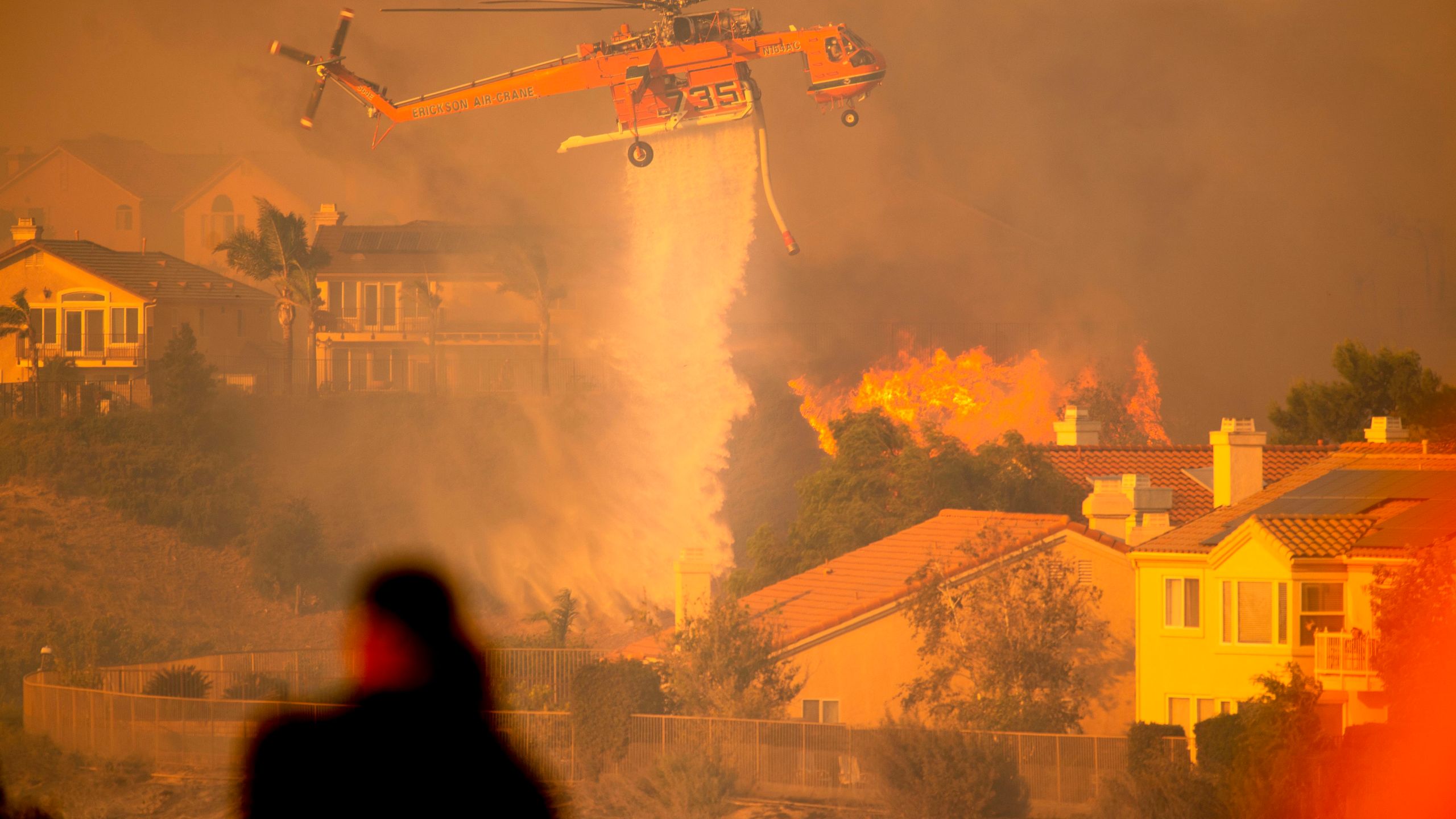 A helicopter drops water to help fight flames as the Saddleridge Fire moves through Porter Ranch on Oct. 11, 2019. (Credit: Josh Edelson / AFP/ Getty Images)