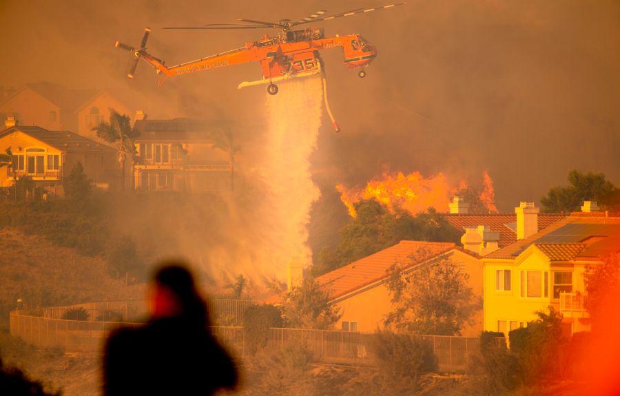 A helicopter drops water to help fight flames as the Saddleridge Fire moves through Porter Ranch on Oct. 11, 2019. (Credit: Josh Edelson / AFP/ Getty Images)