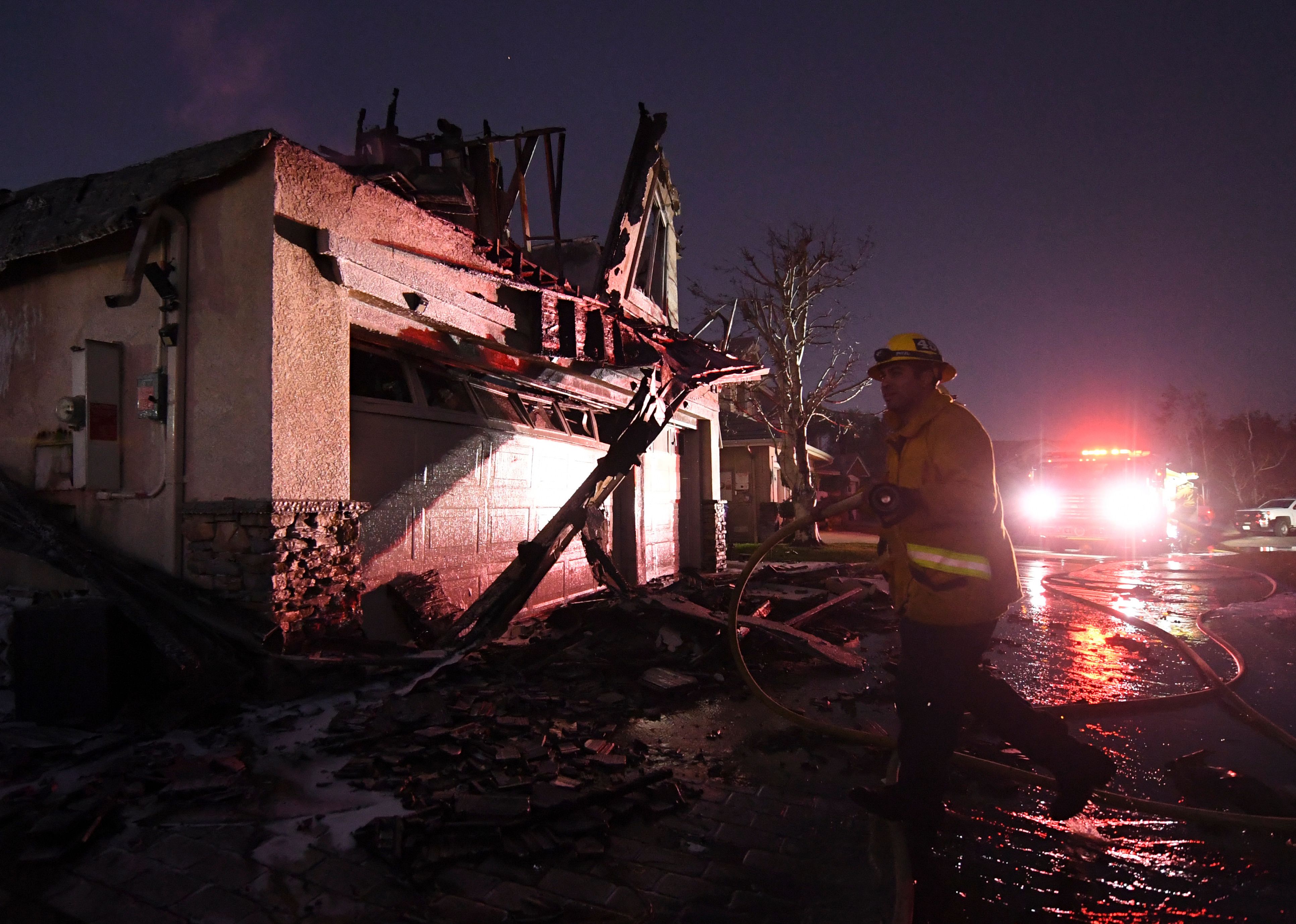 Firefighters hose down a burning house during the Tick Fire in Agua Dulce near Santa Clarita, Calif., on Oct. 25, 2019. (Credit: MARK RALSTON/AFP via Getty Images)