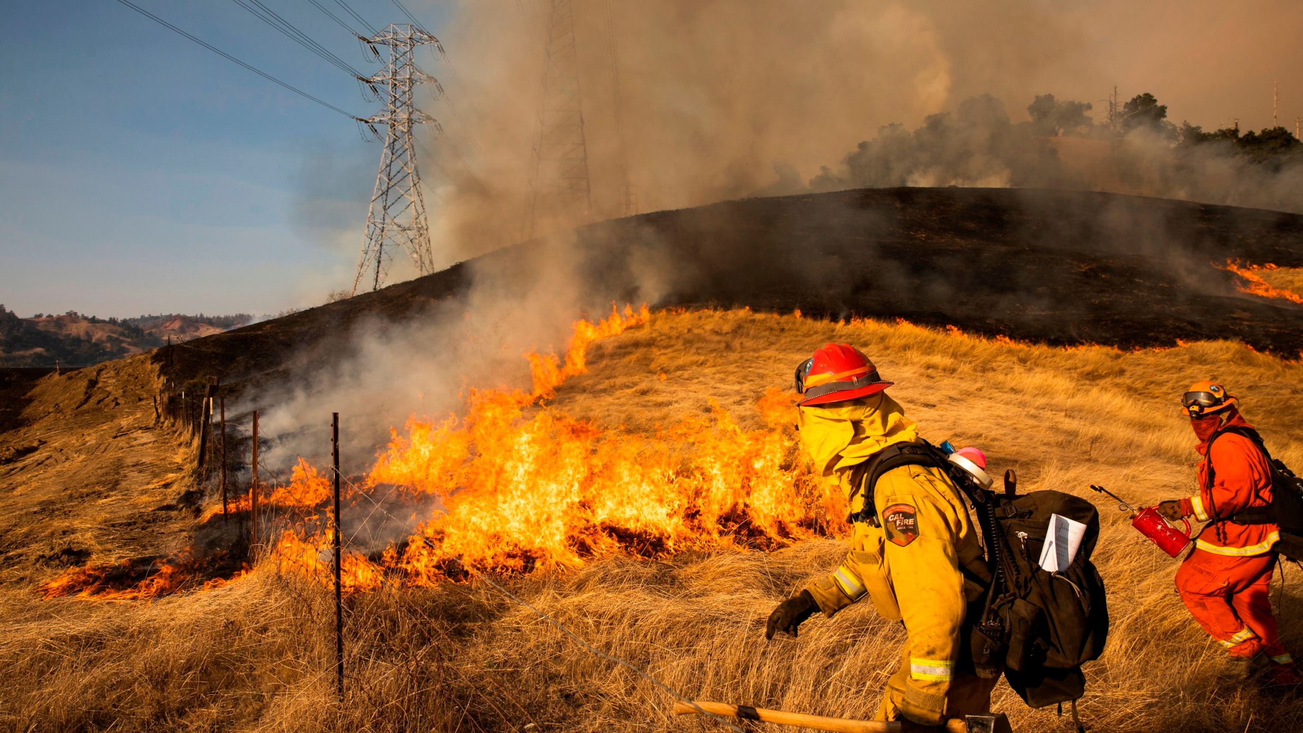 A back fire set by fire fighters burns a hillside near PG&E power lines during firefighting operations to battle the Kincade Fire in Healdsburg, California on Oct. 26, 2019. (Credit: PHILIP PACHECO/AFP via Getty Images)