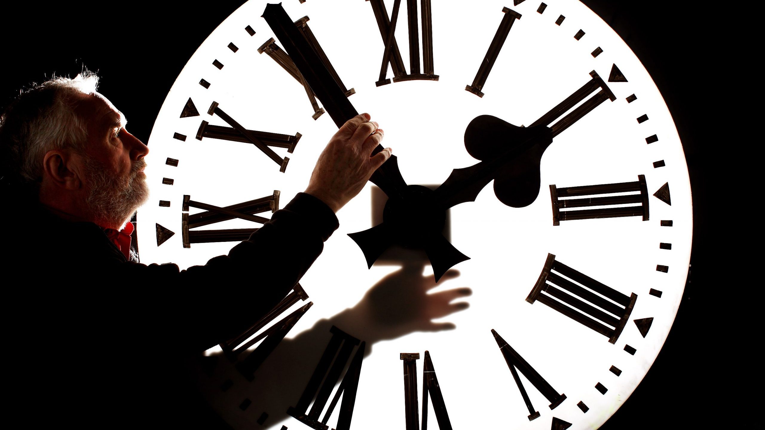 A man adjusts a clock on March 26, 2010, in Edinburgh, Scotland. (Credit: Jeff J Mitchell/Getty Images)