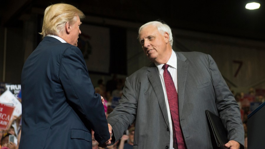 President Donald Trump shakes hands with West Virginia Gov. Jim Justice during a Make America Great Again Rally at Big Sandy Superstore Arena in Huntington, West Virginia, on August 3, 2017. (Credit: SAUL LOEB/AFP/Getty Images)