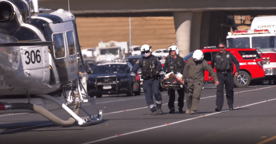 Paramedics transport an injured Ontario Police officer to a helicopter on Interstate 215 in the Grand Terrace area on Oct. 22, 2019. (Credit: RMG News)