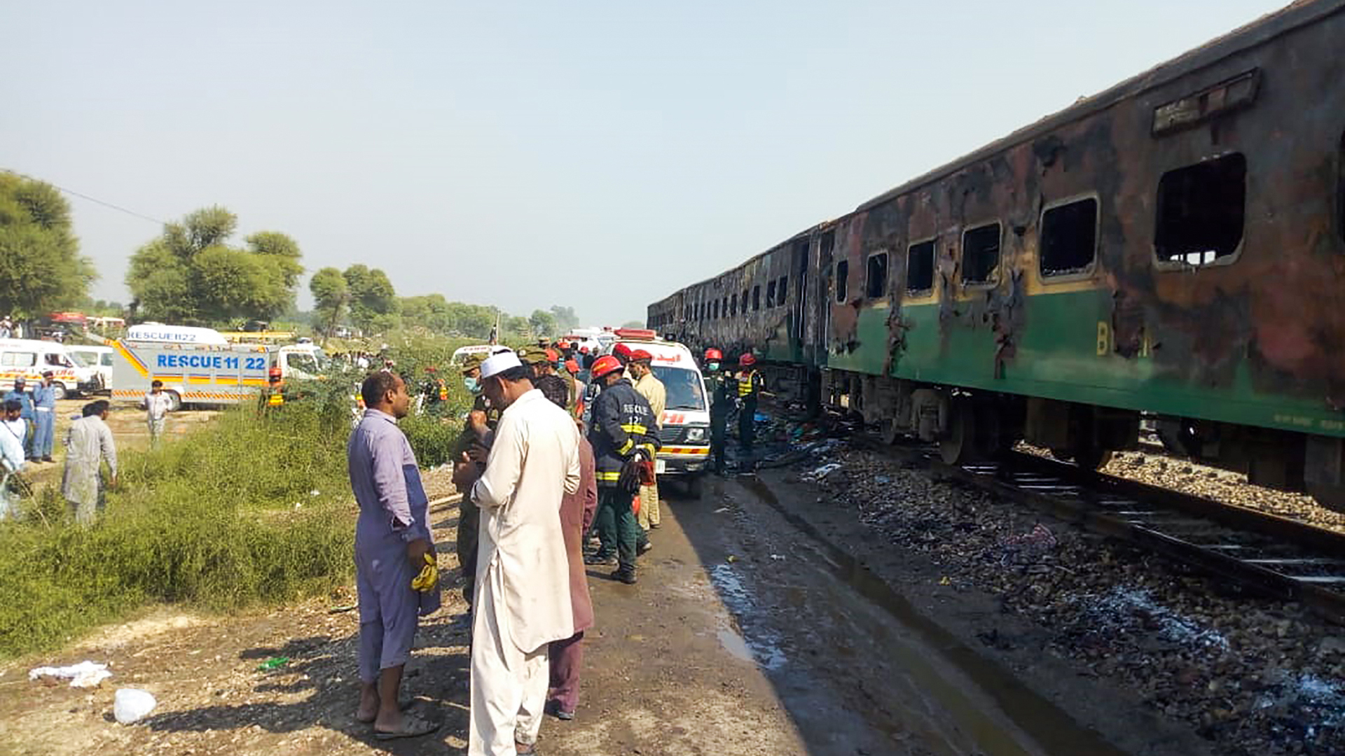 Rescue workers gather beside the burnt-out train carriages after a passenger train caught on fire near Rahim Yar Khan in Punjab province on October 31, 2019. (Credit: AFP via Getty Images)