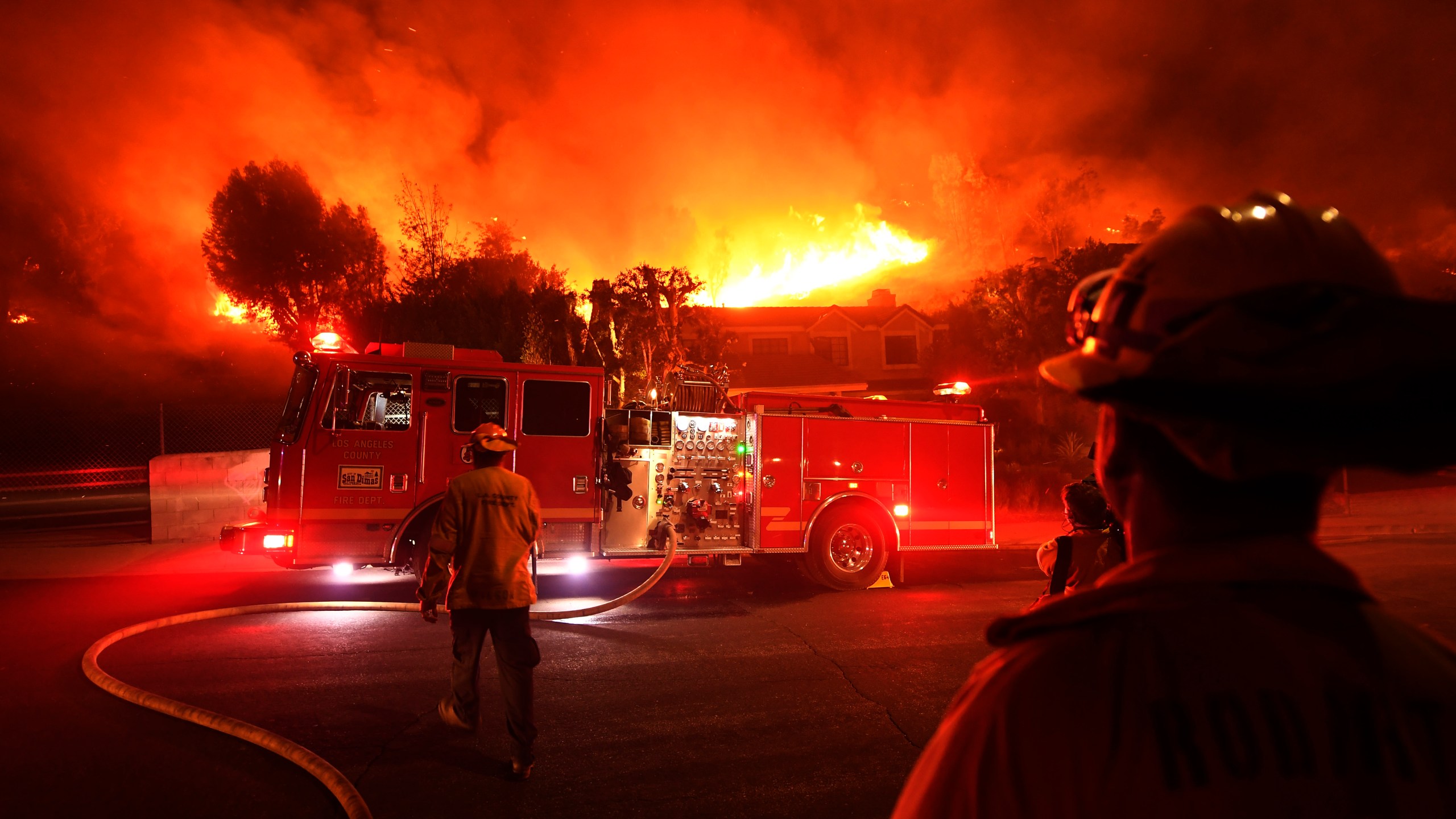 Los Angeles County firefighters look on as the Woolsey Fire explodes behind a house in the West Hills neighborhood on Nov. 9, 2018, in Los Angeles, California. (Credit: Kevork Djansezian/Getty Images)