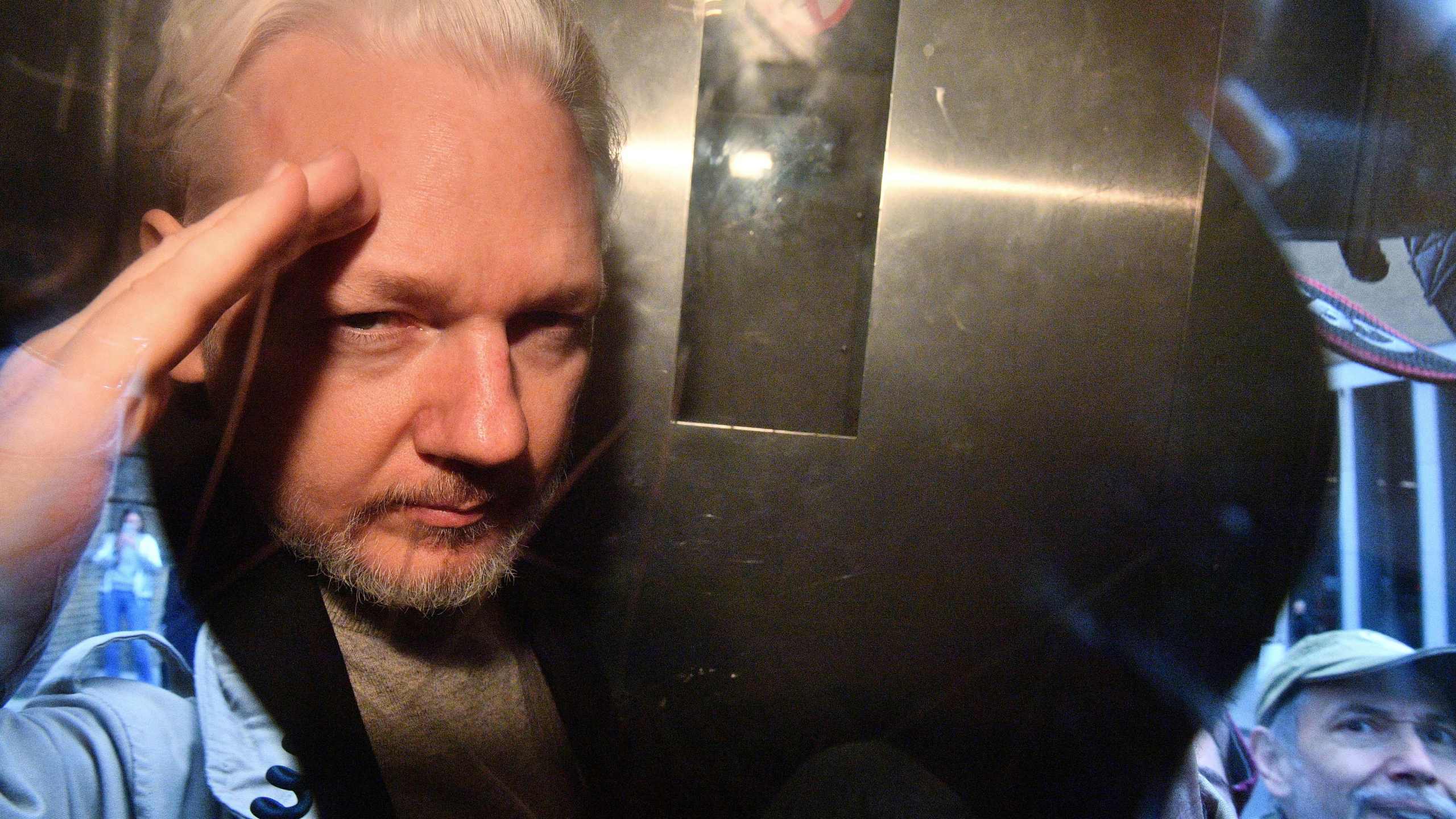 WikiLeaks founder Julian Assange gestures from the window of a prison van as he is driven out of Southwark Crown Court in London on May 1, 2019. (Credit: DANIEL LEAL-OLIVAS/AFP via Getty Images)