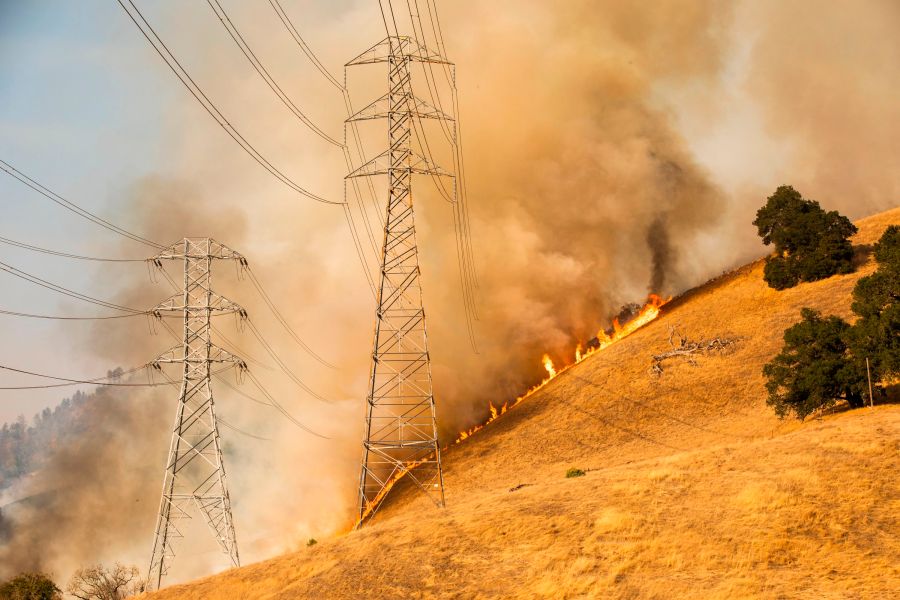 A back fire set by fire fighters burns a hillside behind PG&E power lines during firefighting operations to battle the Kincade Fire in Healdsburg, California, on Oct. 26, 2019. (PHILIP PACHECO/AFP via Getty Images)