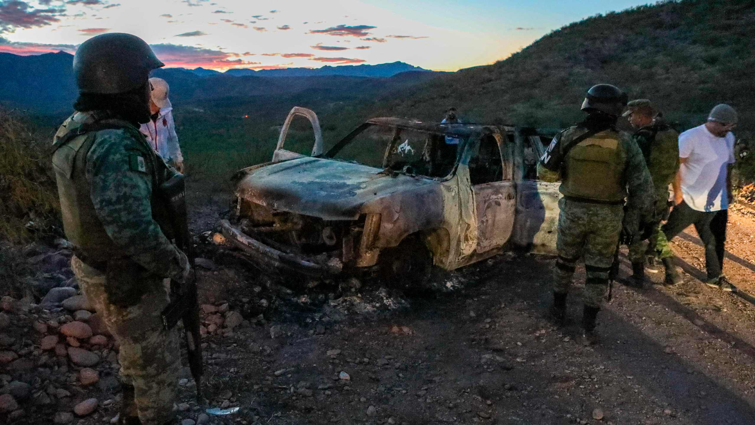 People stand near the burned car where members of the LeBaron family were killed and burned during an ambush in Bavispe, Sonora mountains, Mexico, on Nov. 5, 2019. (Credit: Herika Martinez / AFP / Getty Images)