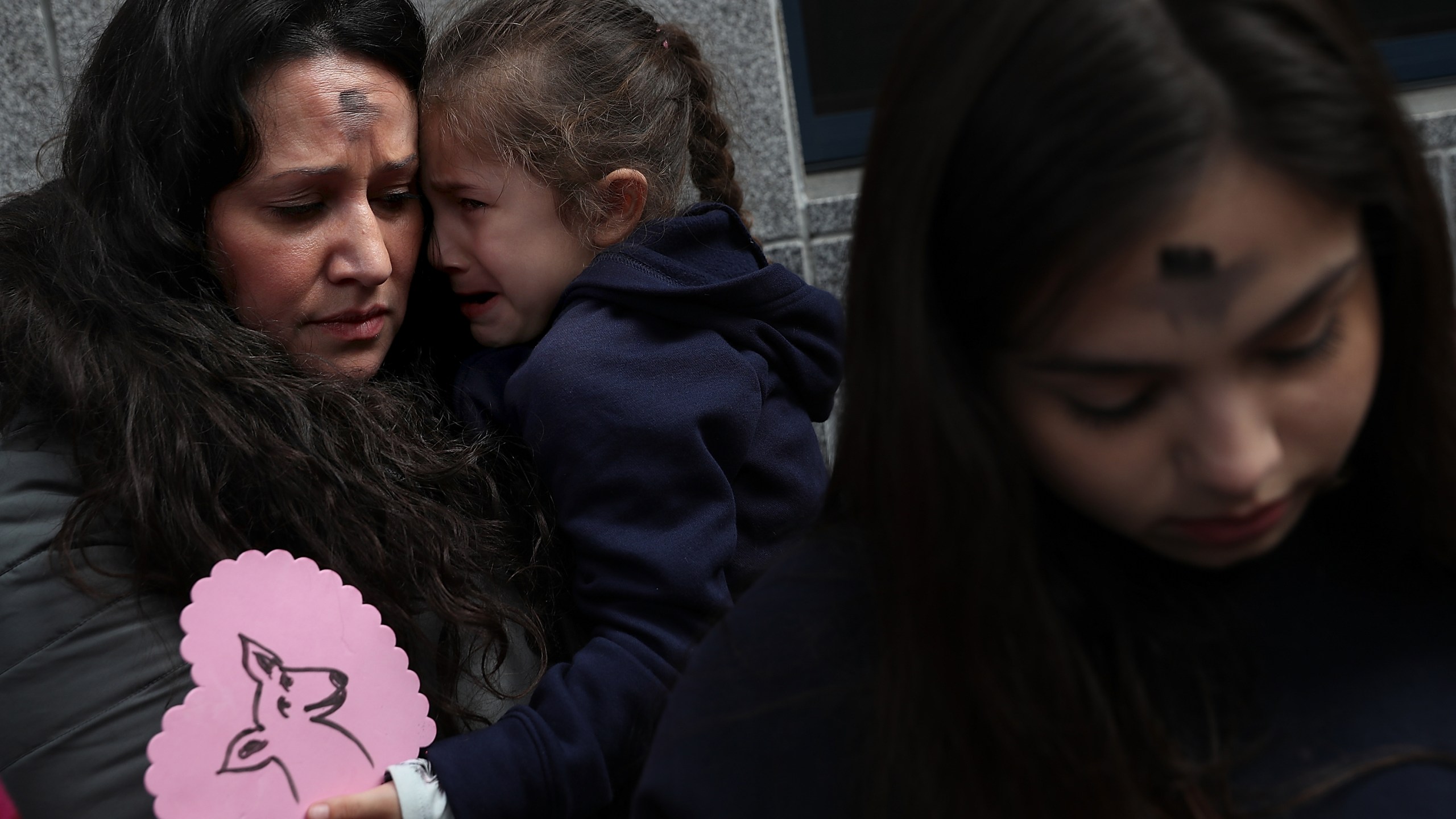 Lourdes Barraza, wife of detained immigrant Fernando Barraza, holds her crying daughter Ana Barraza during a Valentine's Day demonstration outside of the San Francisco office of the Immigration and Cutsoms Enforcement on Feb. 14, 2018 in San Francisco. (Credit: Justin Sullivan/Getty Images)