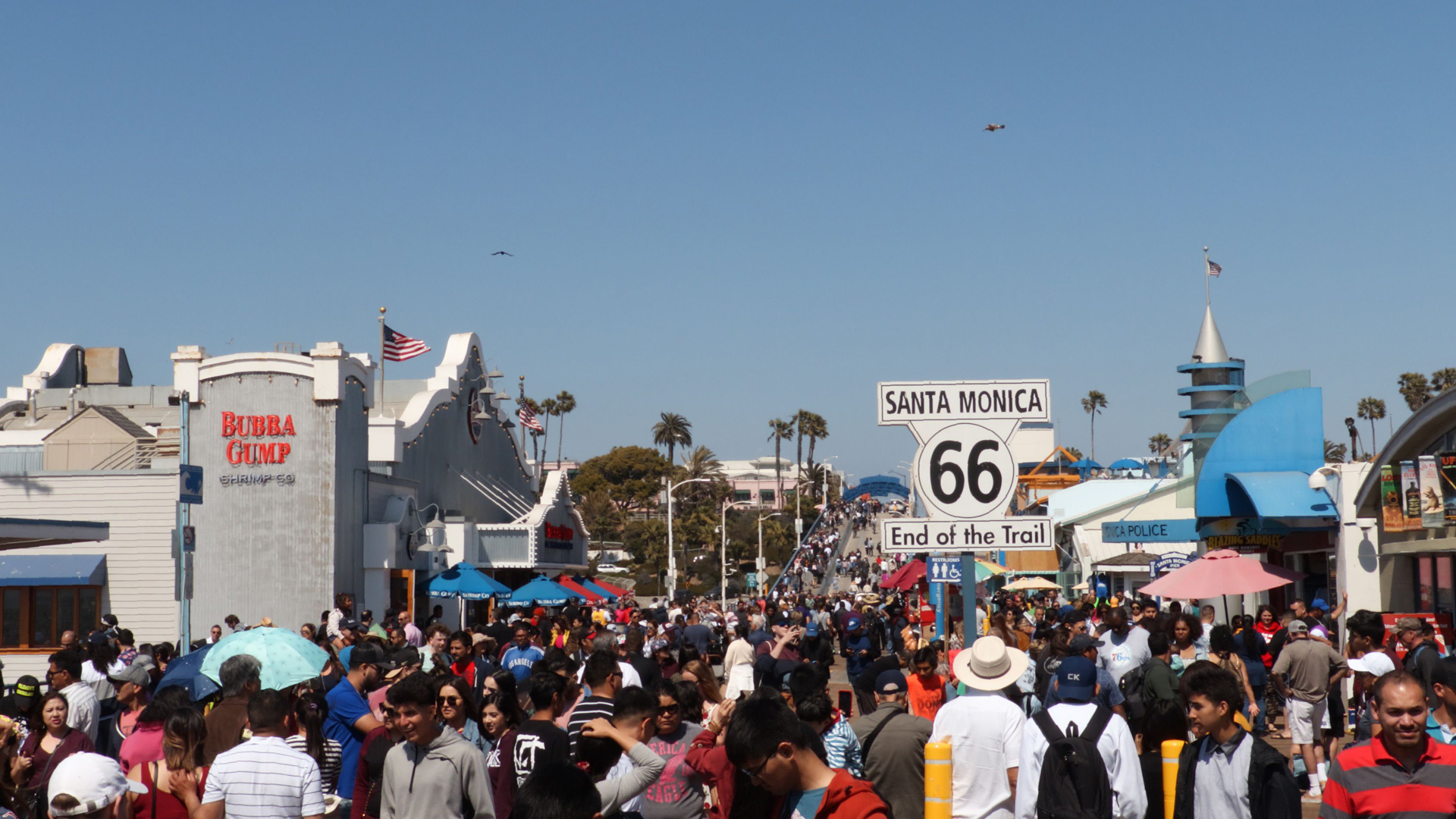 A sign marking the terminus of the historic Route 66 stands in the middle of tourists at Santa Monica Pier on April 21, 2019. (Credit: Daniel Slim / AFP / Getty Images)