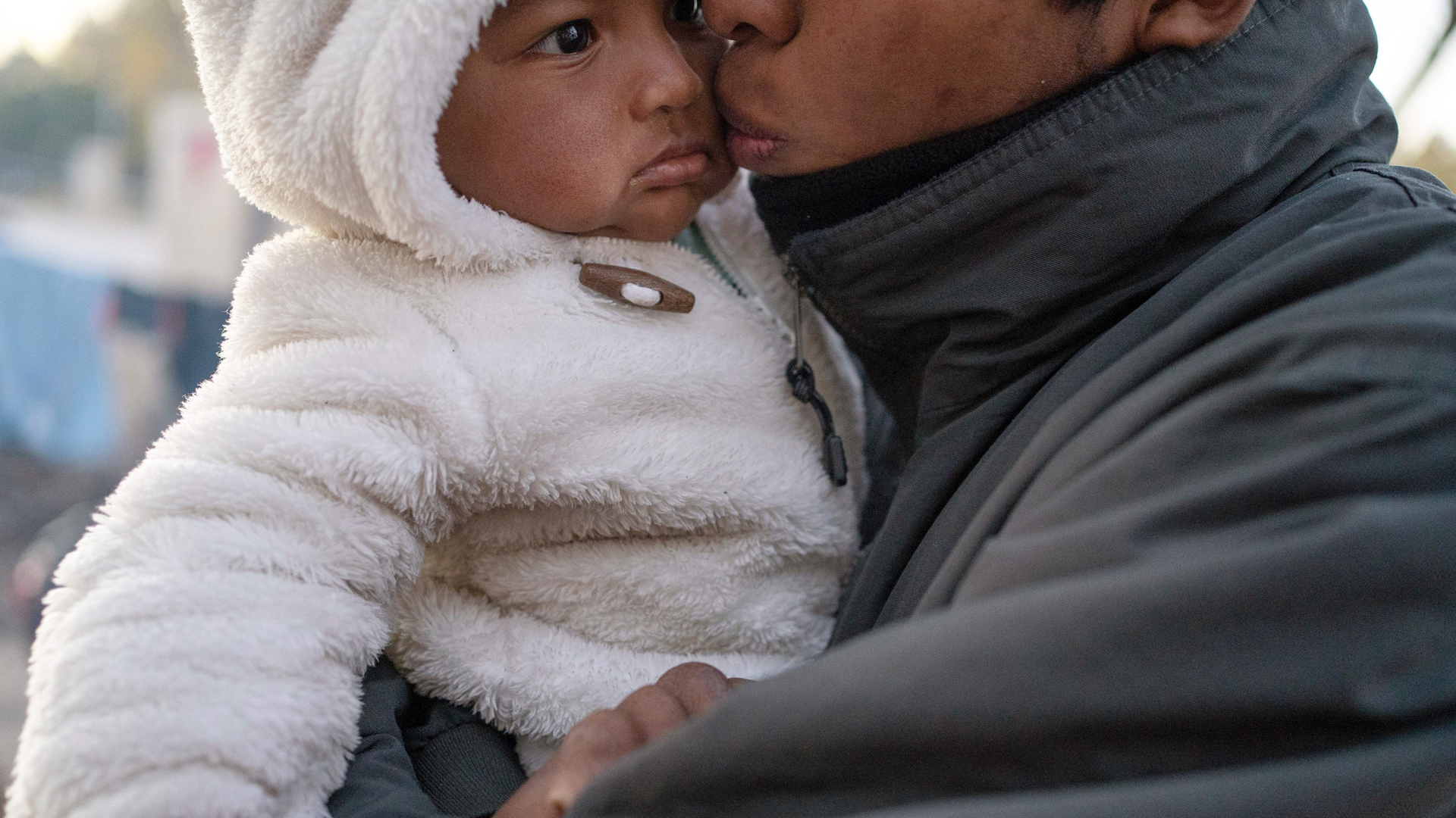 An unidentified man from Guerrero State, who is fleeing cartel violence, kisses his daughter as they prepare for another cold night in the camp on Dec. 10, 2019, in Ciudad Juarez, Mexico. In the mud and biting cold of a makeshift camp in the border city of Ciudad Juarez, more than 1,000 Mexican migrants had been waiting for weeks, some for months, for a chance to file for asylum in the United States. (Credit: PAUL RATJE/AFP via Getty Images)