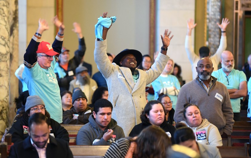 People who support legalizing and regulating short-term rentals of second homes wave their hands in agreement with a speaker during a Planning Commission meeting at Los Angeles City Hall on Dec. 19, 2019. (Credit: Wally Skalij / Los Angeles Times)