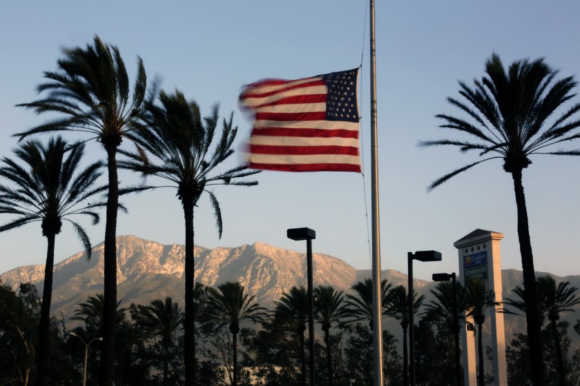 Winds whip palm trees and a U.S. flag in this undated photo. (Irfan Khan / Los Angeles Times)