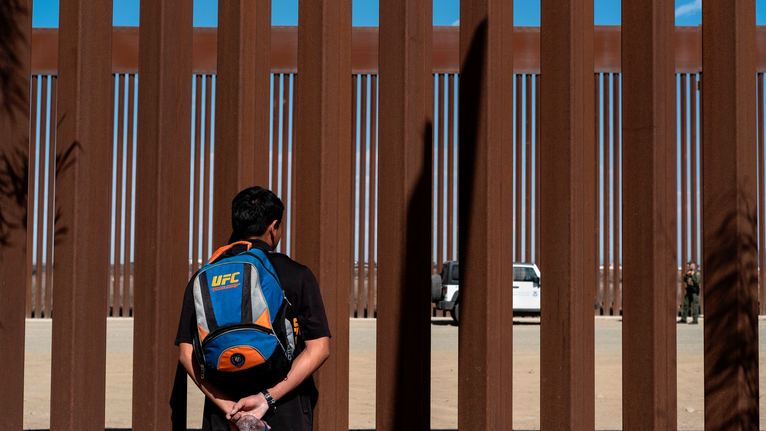 A migrant from Guatemala watches border patrol officers through the border fence at the Mexican side of the U.S.-Mexico border in Tijuana, Mexico, on Nov. 2, 2019. (Credit: Guillermo Arias/AFP via Getty Images)