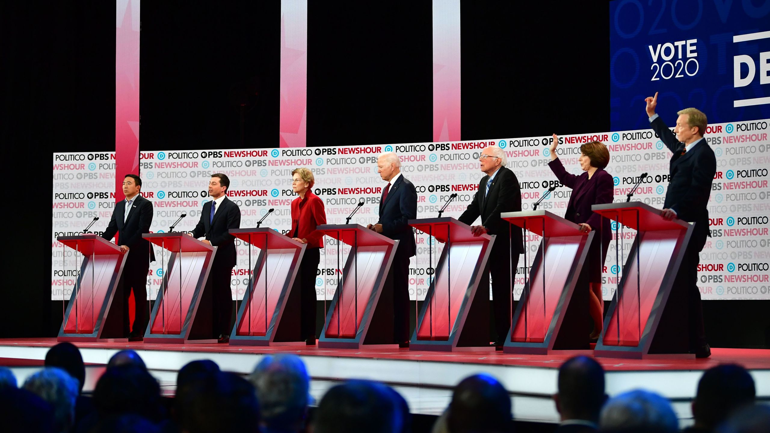 From left, Democratic presidential hopefuls entrepreneur Andrew Yang, South Bend Mayor Pete Buttigieg, Massachusetts Sen. Elizabeth Warren, former Vice President Joe Biden, Vermont Sen. Bernie Sanders, Minnesota Sen. Amy Klobuchar and businessman Tom Steyer participate at the sixth Democratic primary debate at Loyola Marymount University on Dec. 19, 2019. (Credit: Frederic J. Brown / AFP / Getty Images)