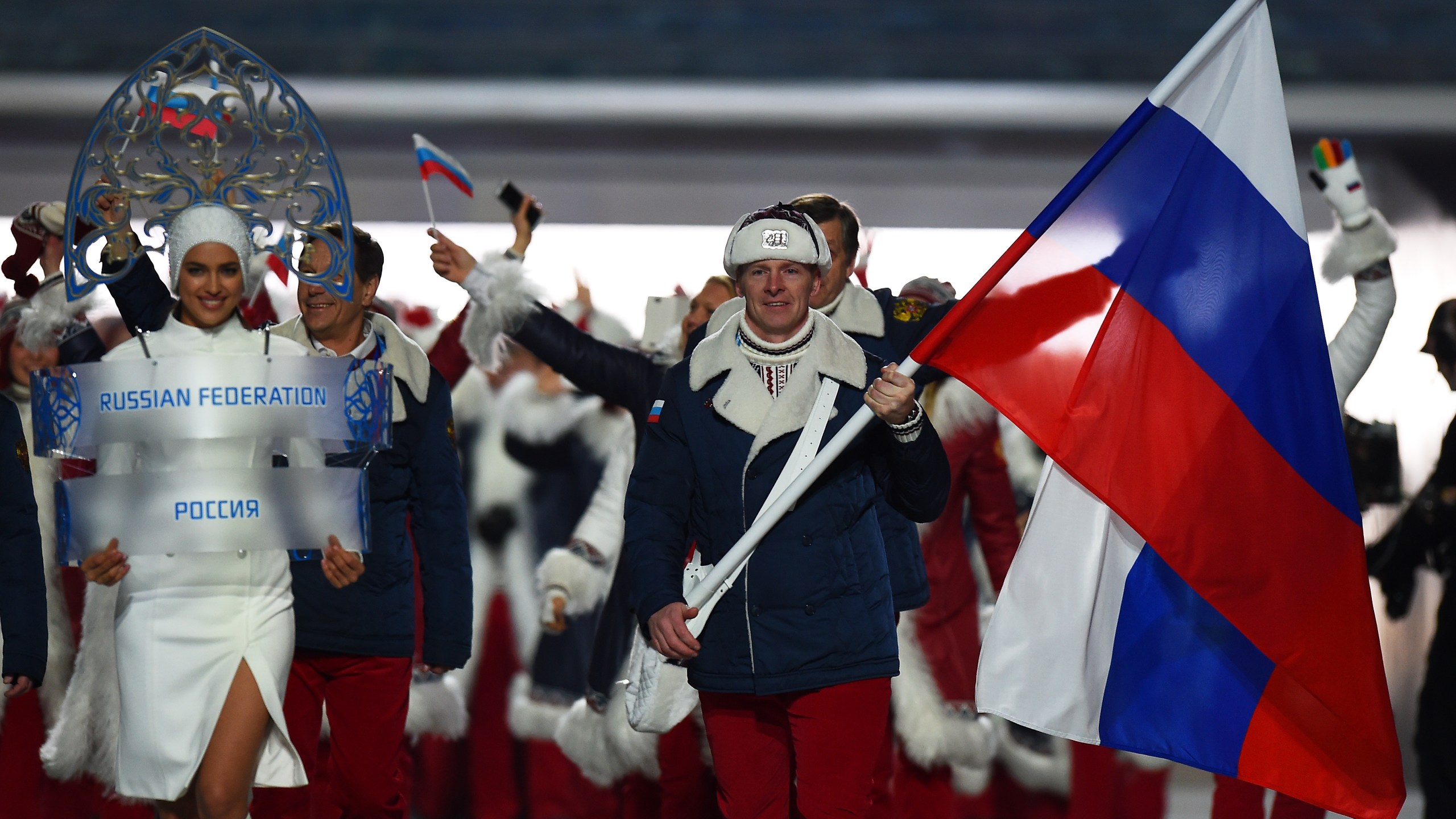 Bobsleigh racer Alexander Zubkov of the Russia Olympic team carries his country's flag alongside model Irina Shayk (left) during the Opening Ceremony of the Sochi 2014 Winter Olympics at Fisht Olympic Stadium on February 7, 2014 in Sochi, Russia. (Credit: Pascal Le Segretain/Getty Images)