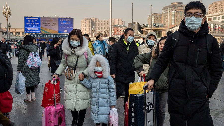 People wearing protective masks arrive at Beijing railway station to head home for the Lunar New Year on January 21, 2020. (Credit: NICOLAS ASFOURI/AFP via Getty Images)