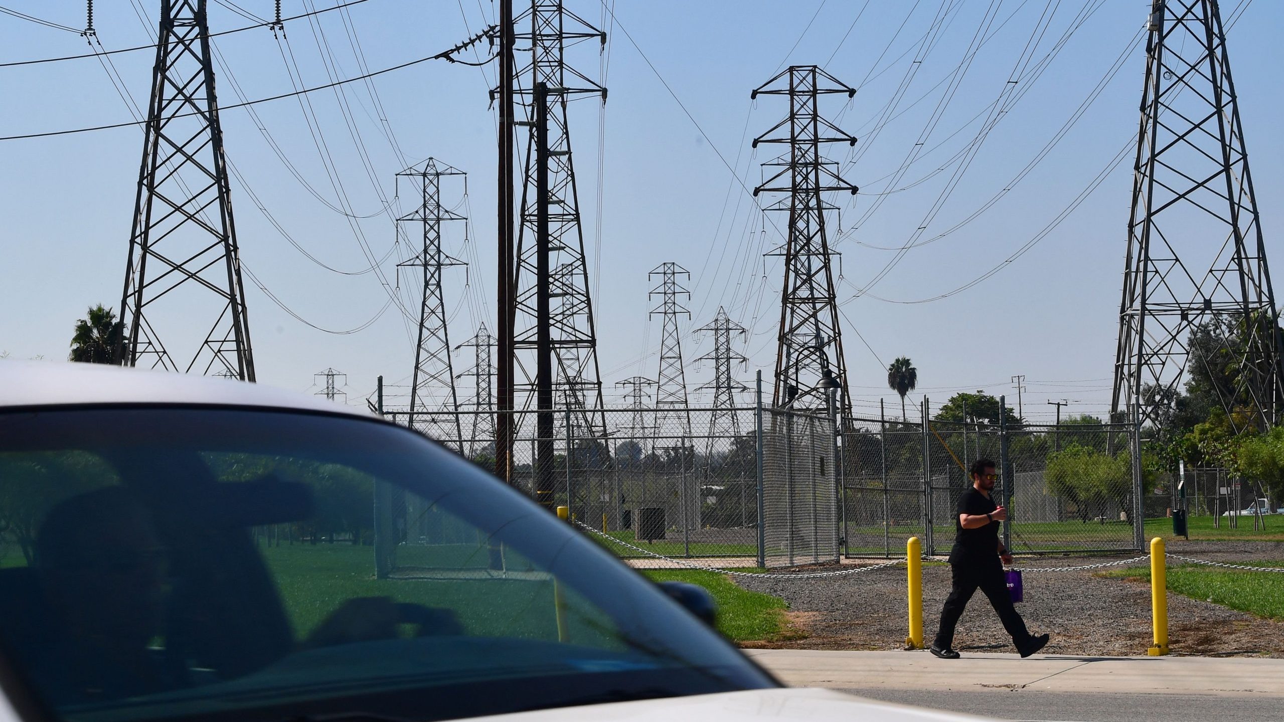 A pedestrian and motorist pass a row of power lines in Rosemead on Oct. 9, 2019. (Frederic J. Brown / AFP / Getty Images)