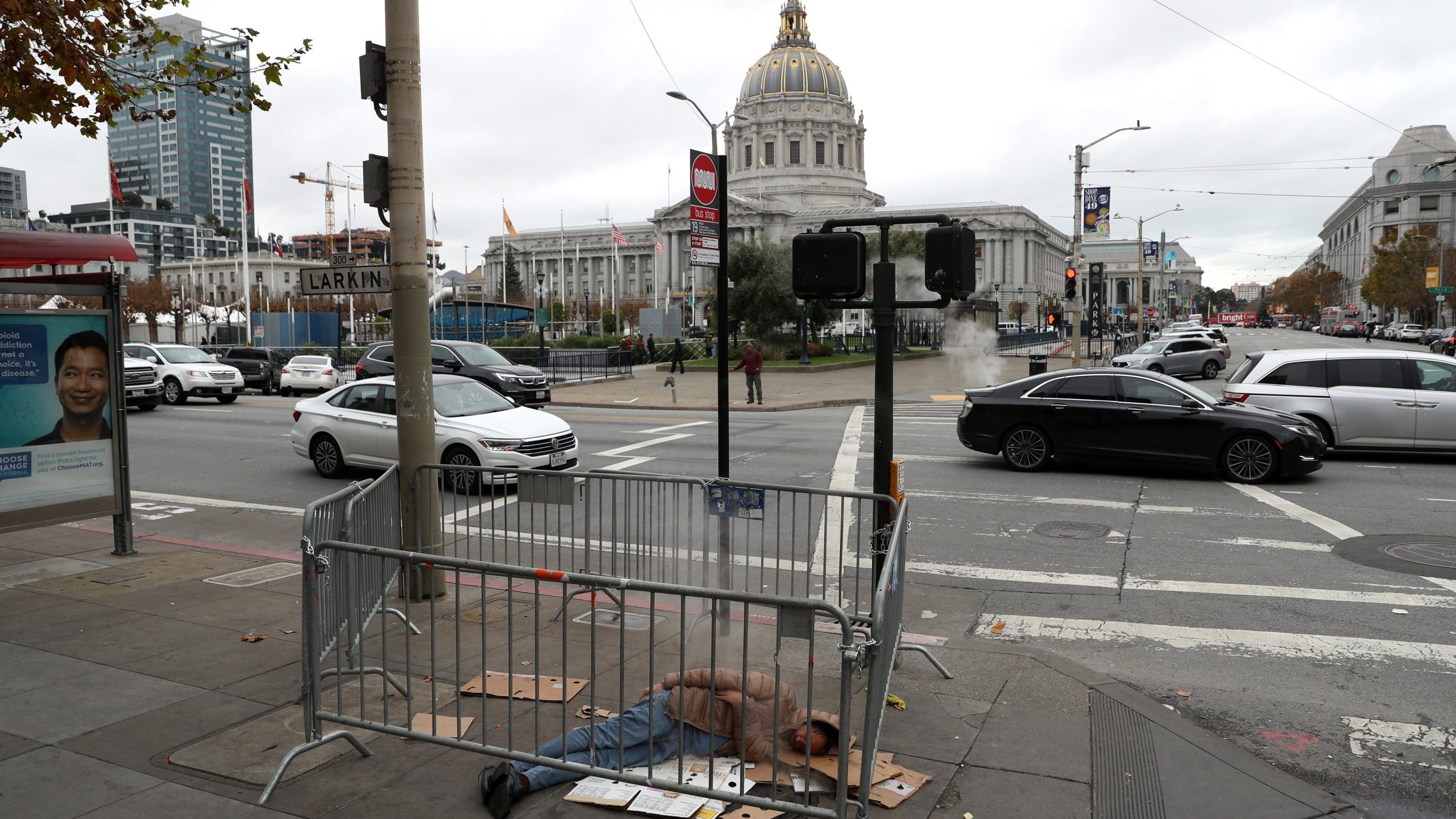 A homeless man sleeps on the sidewalk near San Francisco City Hall on Dec. 5, 2019, in San Francisco, California. (Credit: Justin Sullivan/Getty Images)