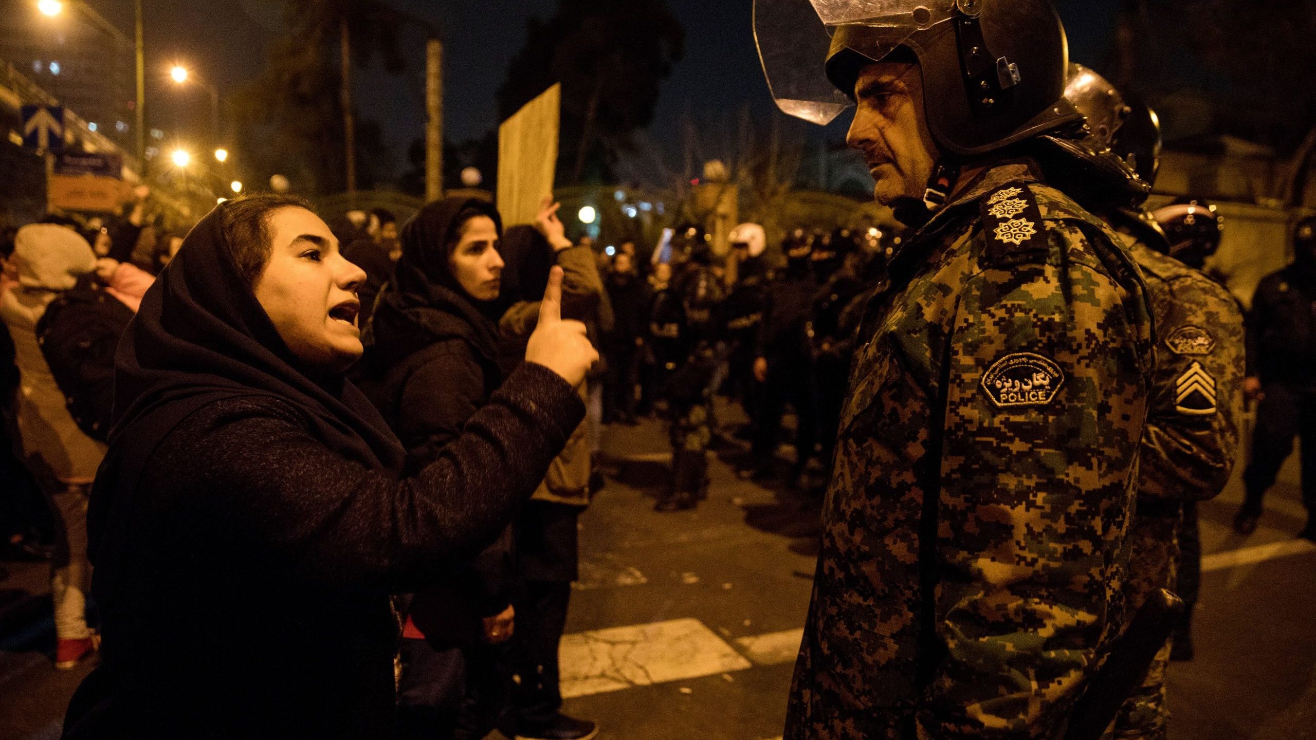 A woman attending a candlelight vigil, in memory of the victims of Ukraine International Airlines Boeing 737, talks to a policeman following the gathering in front of the Amirkabir University in the Iranian capital Tehran on Jan. 11, 2020. (Credit: MONA HOOBEHFEKR/ISNA/AFP via Getty Images)