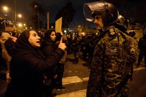 A woman attending a candlelight vigil, in memory of the victims of Ukraine International Airlines Boeing 737, talks to a policeman following the gathering in front of the Amirkabir University in the Iranian capital Tehran on Jan. 11, 2020. (Credit: MONA HOOBEHFEKR/ISNA/AFP via Getty Images)