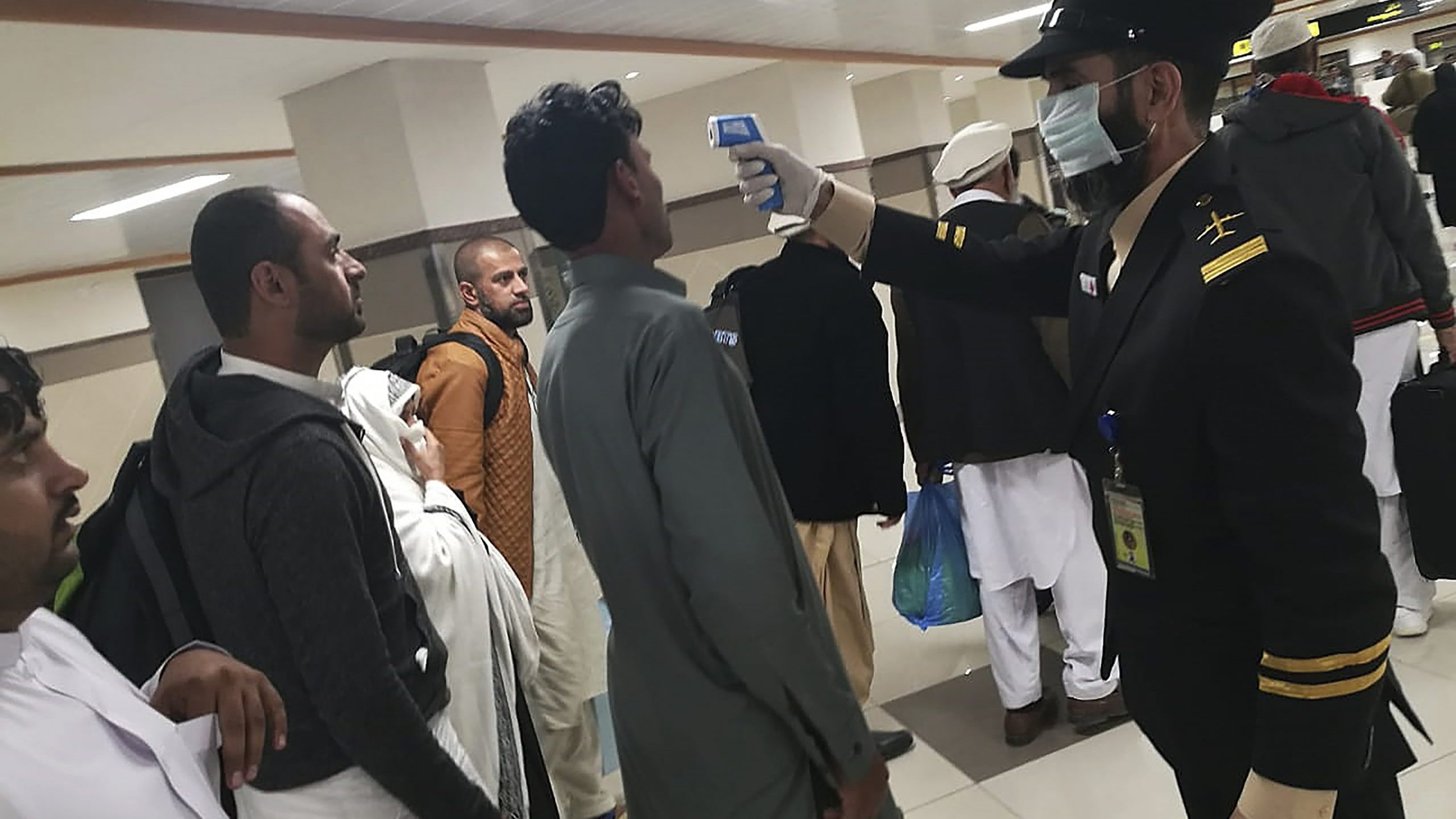 An airport official checks the temperature of a passenger upon his arrival at the Bacha Khan International Airport in Peshawar on January 27, 2020.