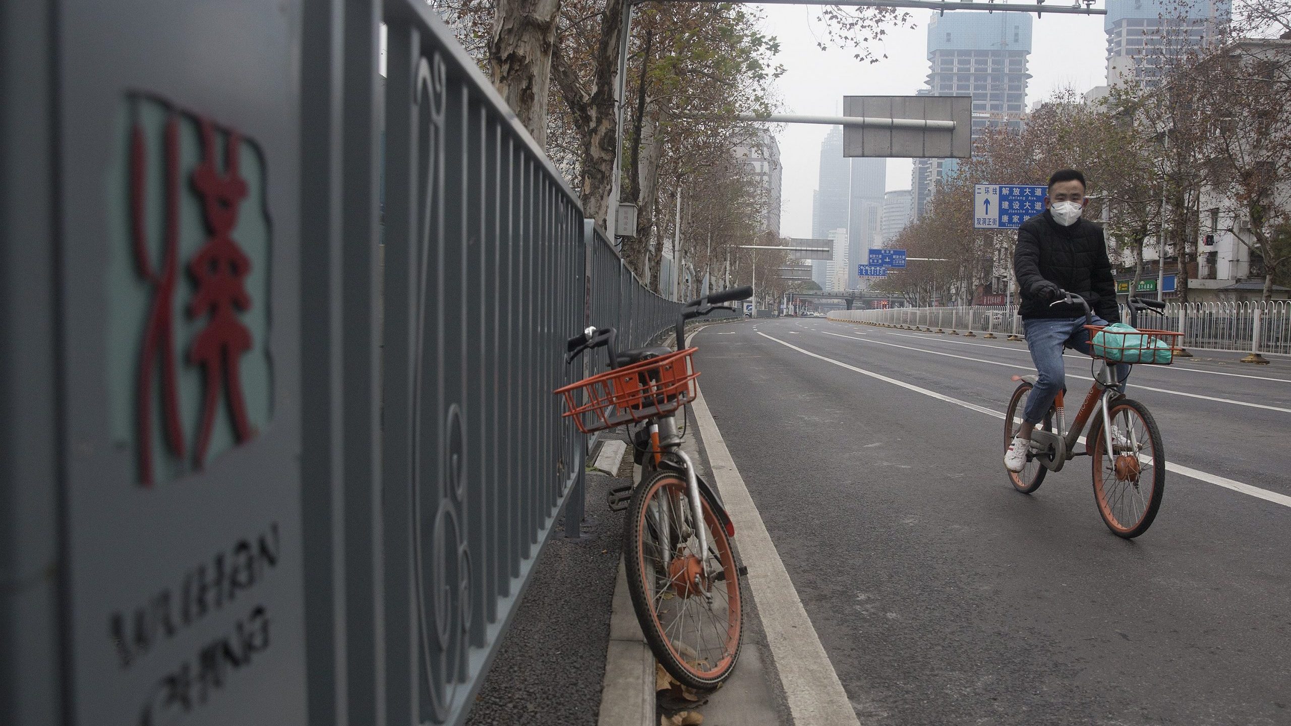 A man wearing a protective mask rides a motorized bike on an empty road on Jan. 27, 2020, in Wuhan, China. (Credit: Getty Images)