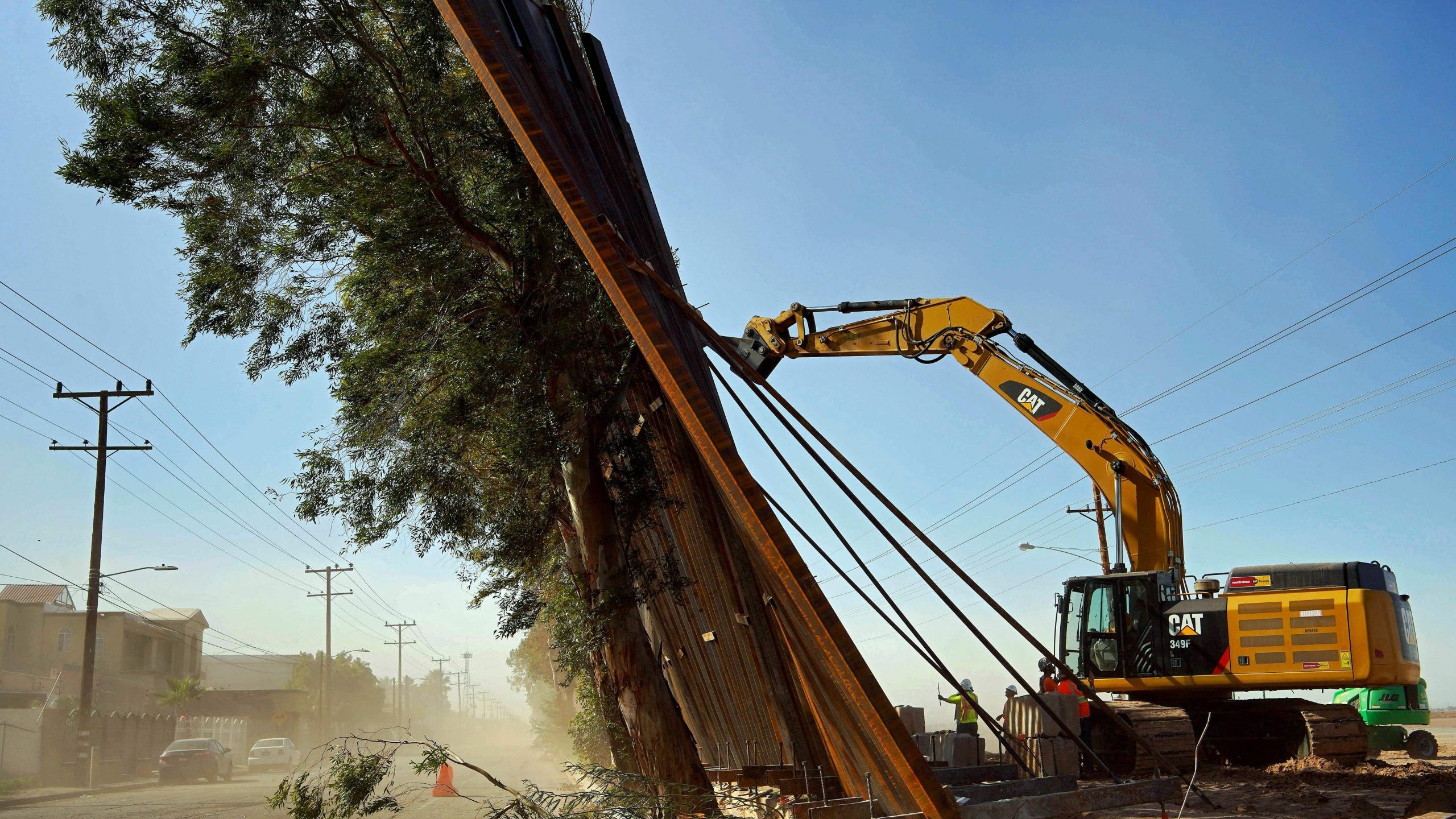 A construction crew works on a fallen section of the U.S.-Mexico border wall as seen from Mexico on Jan. 29, 2020. (Credit: STR/AFP via Getty Images)