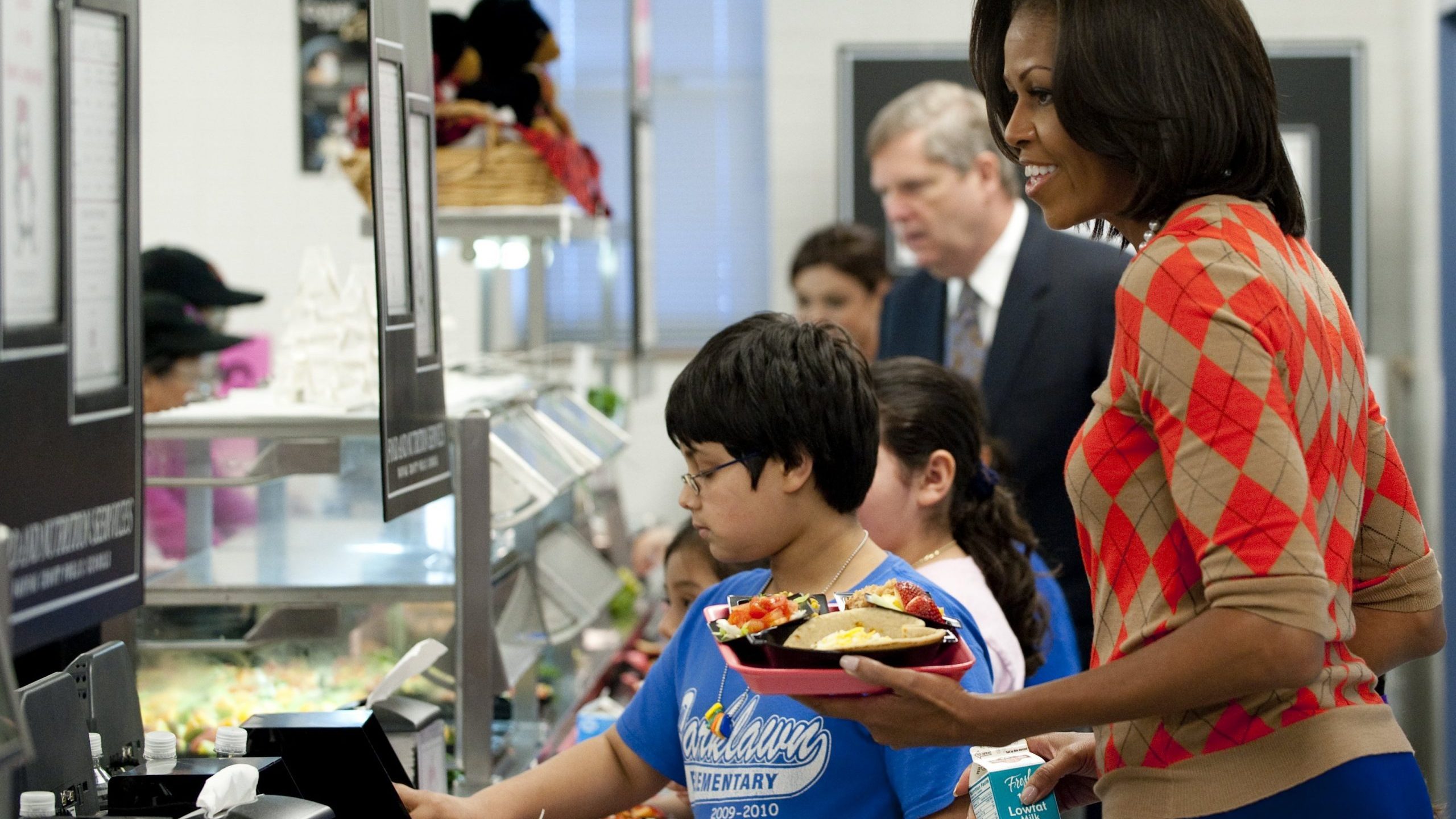 Michelle Obama holds a plate of food while walking down the school lunch line in the cafeteria at Parklawn Elementary School in Alexandria, Virginia, on Jan. 25, 2012. (Credit: SAUL LOEB/AFP via Getty Images)