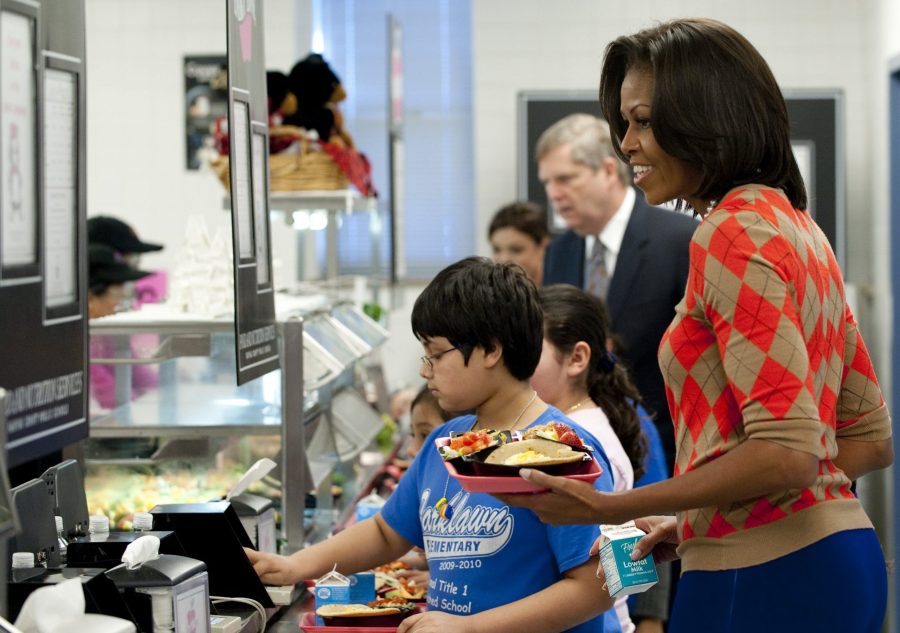 Michelle Obama holds a plate of food while walking down the school lunch line in the cafeteria at Parklawn Elementary School in Alexandria, Virginia, on Jan. 25, 2012. (Credit: SAUL LOEB/AFP via Getty Images)