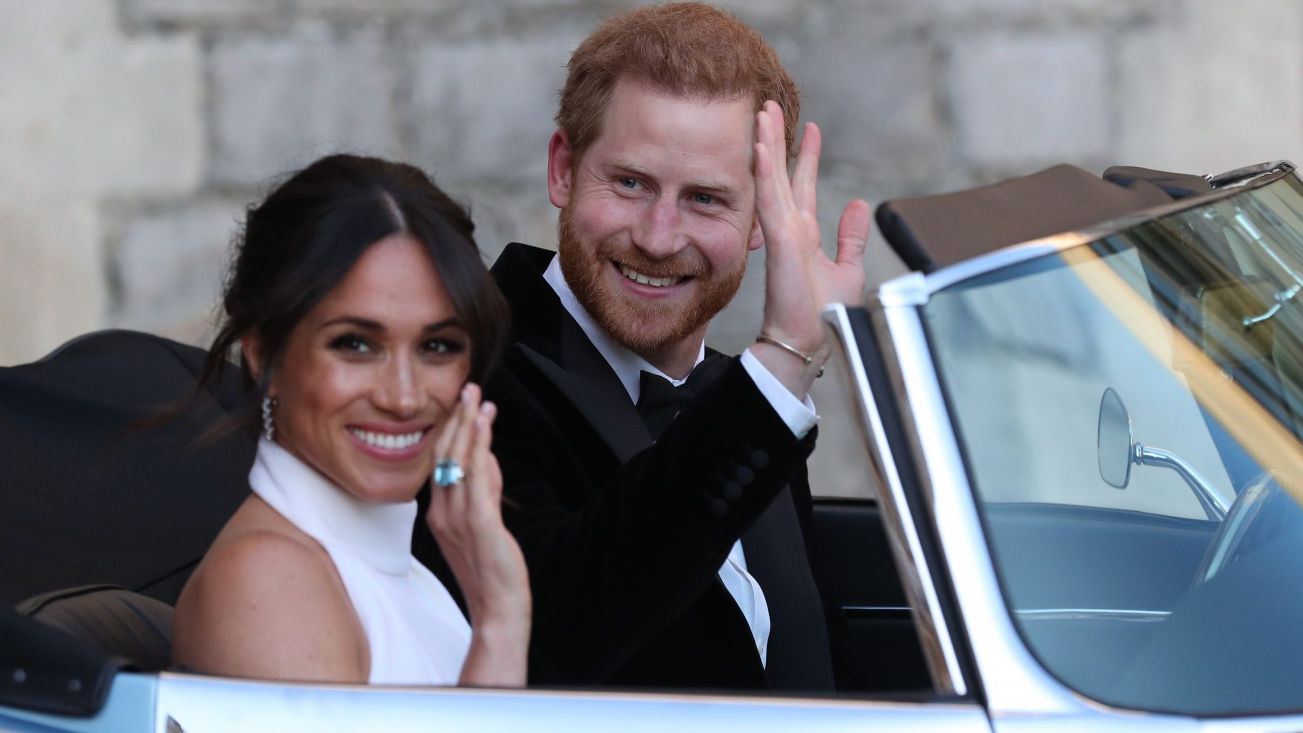 Duchess of Sussex and Prince Harry, Duke of Sussex wave as they leave Windsor Castle after their wedding to attend an evening reception at Frogmore House, hosted by the Prince of Wales on May 19, 2018 in Windsor, England. (Credit: Steve Parsons - WPA Pool/Getty Images)