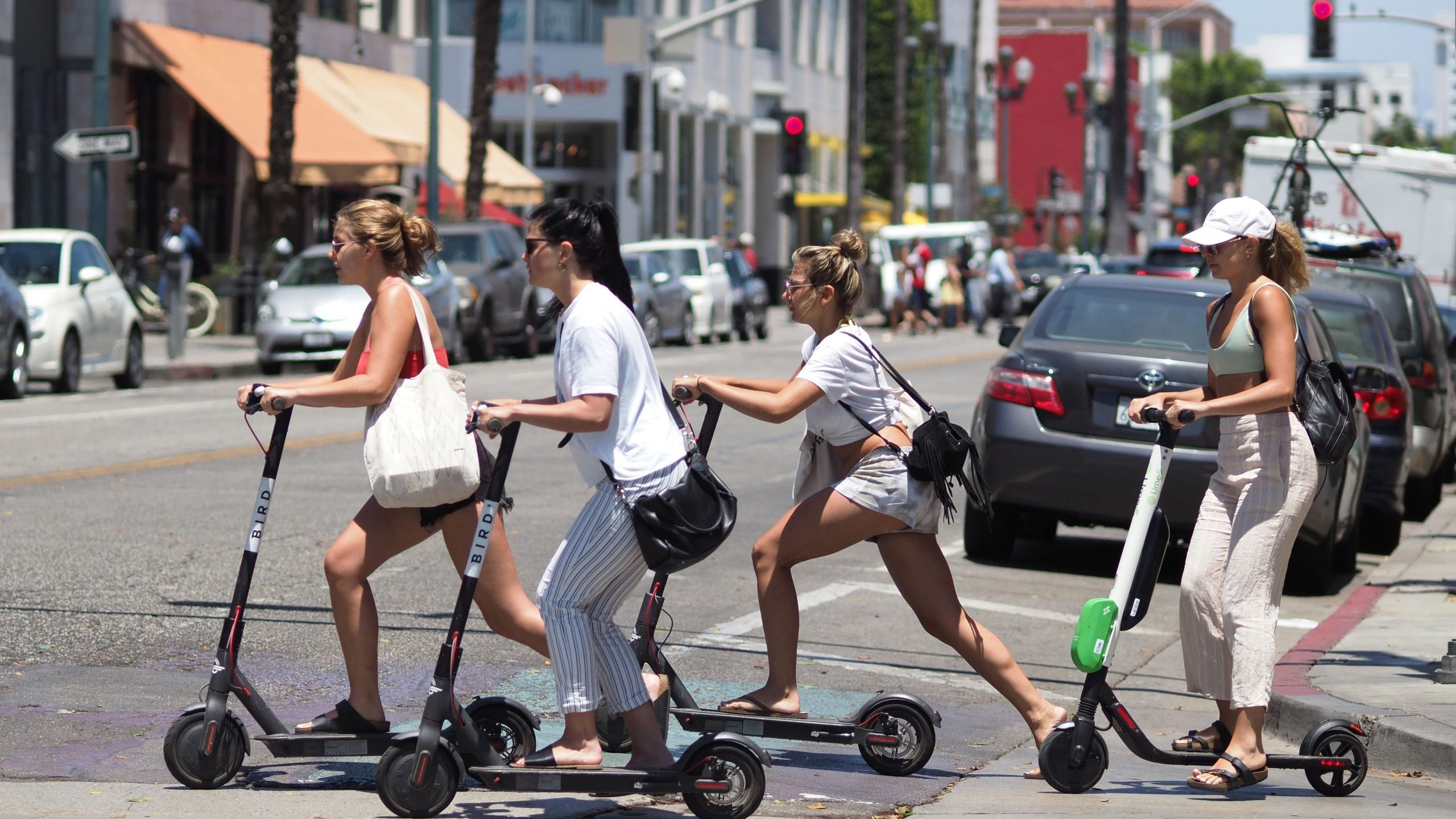 Young women ride electric scooters in Santa Monica on July 13, 2018. (Credit: Robyn Beck/AFP via Getty Images)