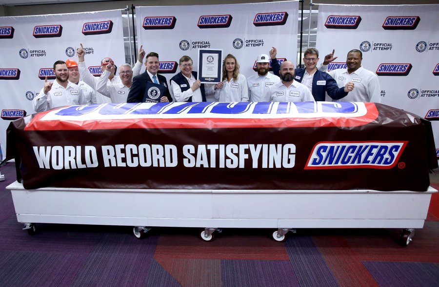 Mars Wrigley employees pose with a giant Snickers bar made at the plant in Waco, Texas. (Credit: Jerry Larson/AP via CNN Wire)