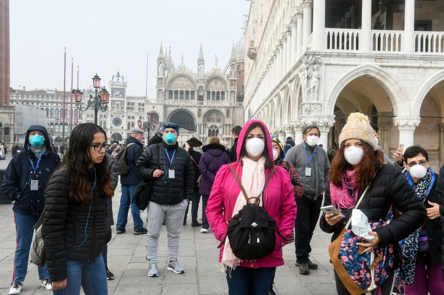 Tourists wearing protective masks visit Venice, Italy on Feb. 25, 2020, during the usual period of the Carnival festivities which have been cancelled following an outbreak of the COVID-19 novel coronavirus in northern Italy. (ANDREA PATTARO/AFP via Getty Images)