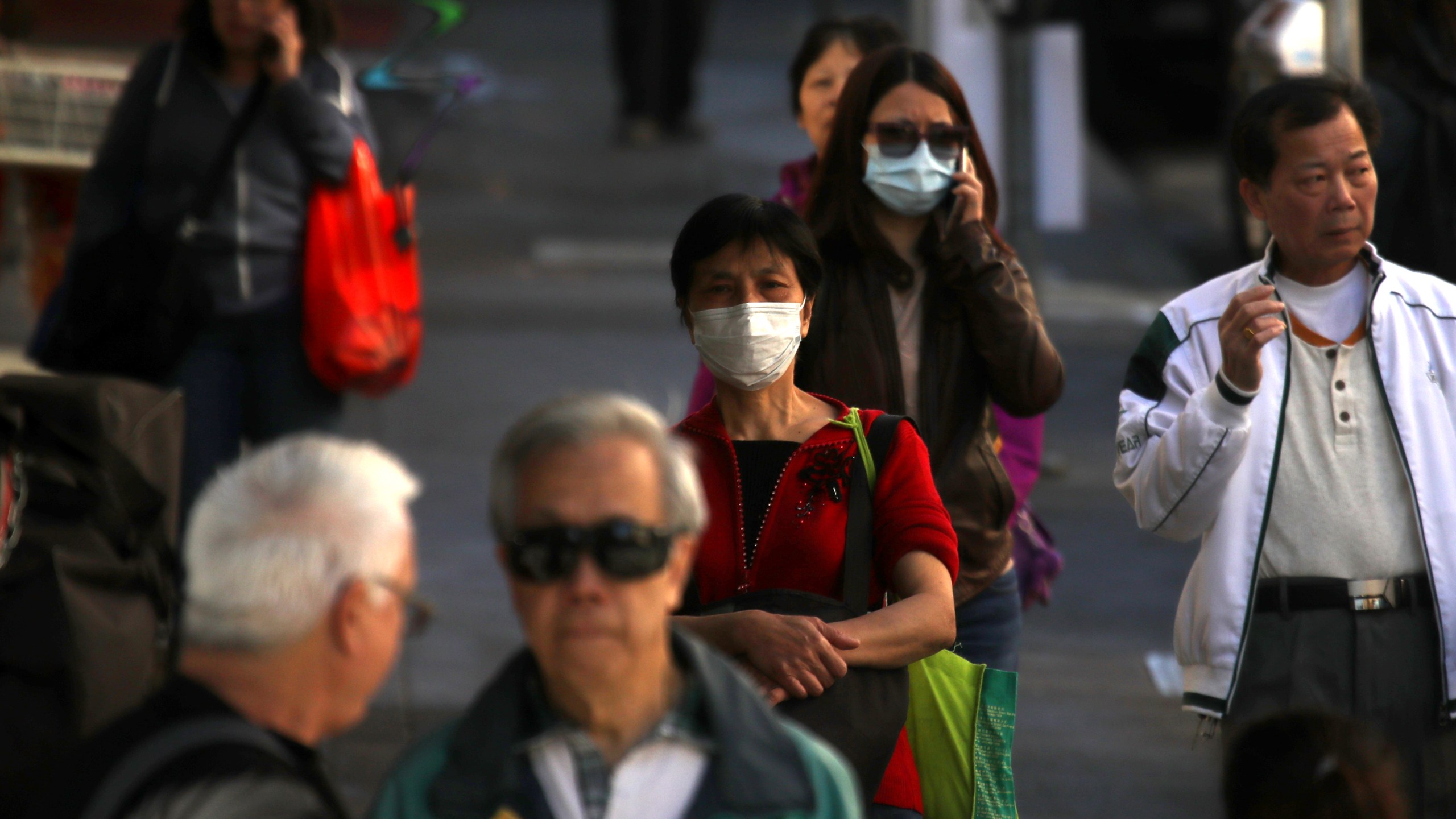 People wear surgical masks as they walk along Grant Avenue in San Francisco’s Chinatown on Feb. 26, 2020. (Credit: Justin Sullivan / Getty Images)