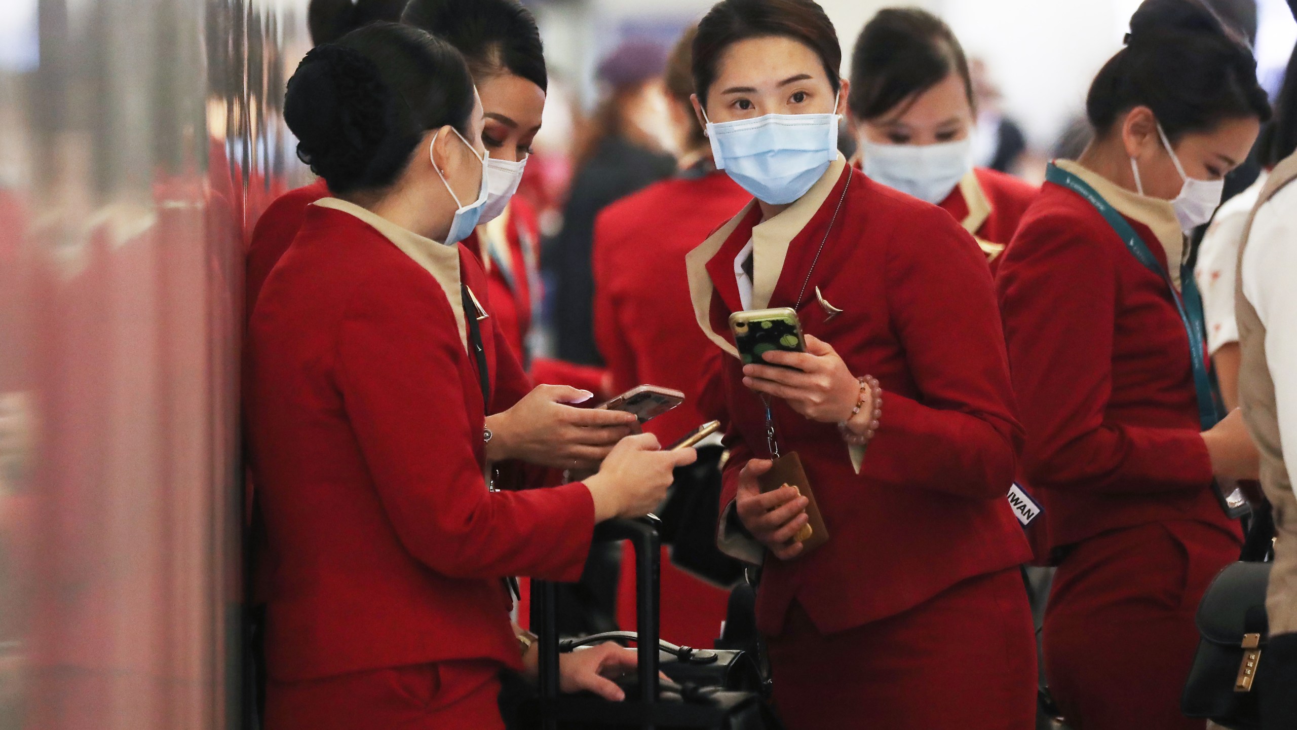 A flight crew from Cathay Pacific Airways, wearing protective masks, stand in the international terminal at Los Angeles International Airport after arriving on a flight from Hong Kong on Feb. 28, 2020. (Credit: Mario Tama / Getty Images)