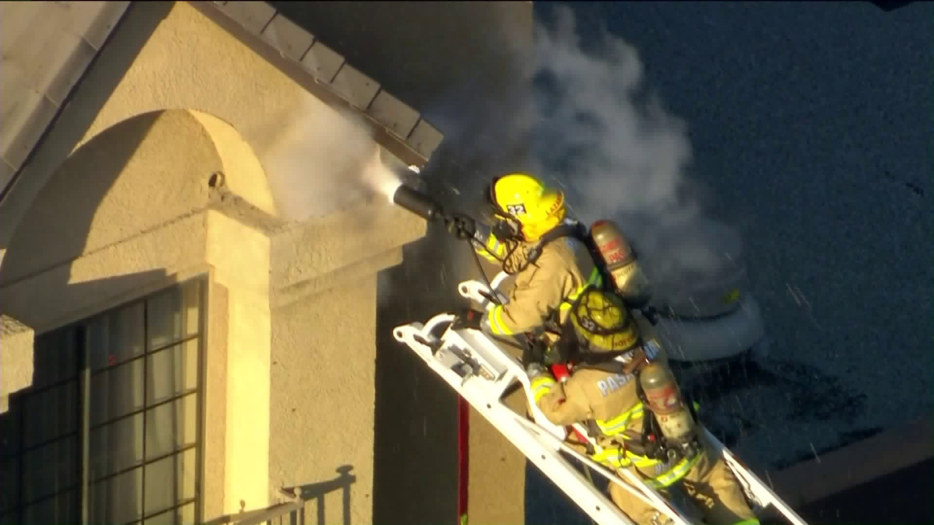 Firefighters work to remove a bee hive at 1599 East Colorado Blvd. atop Howard Johnson Inn in Pasadena. (Credit KTLA)